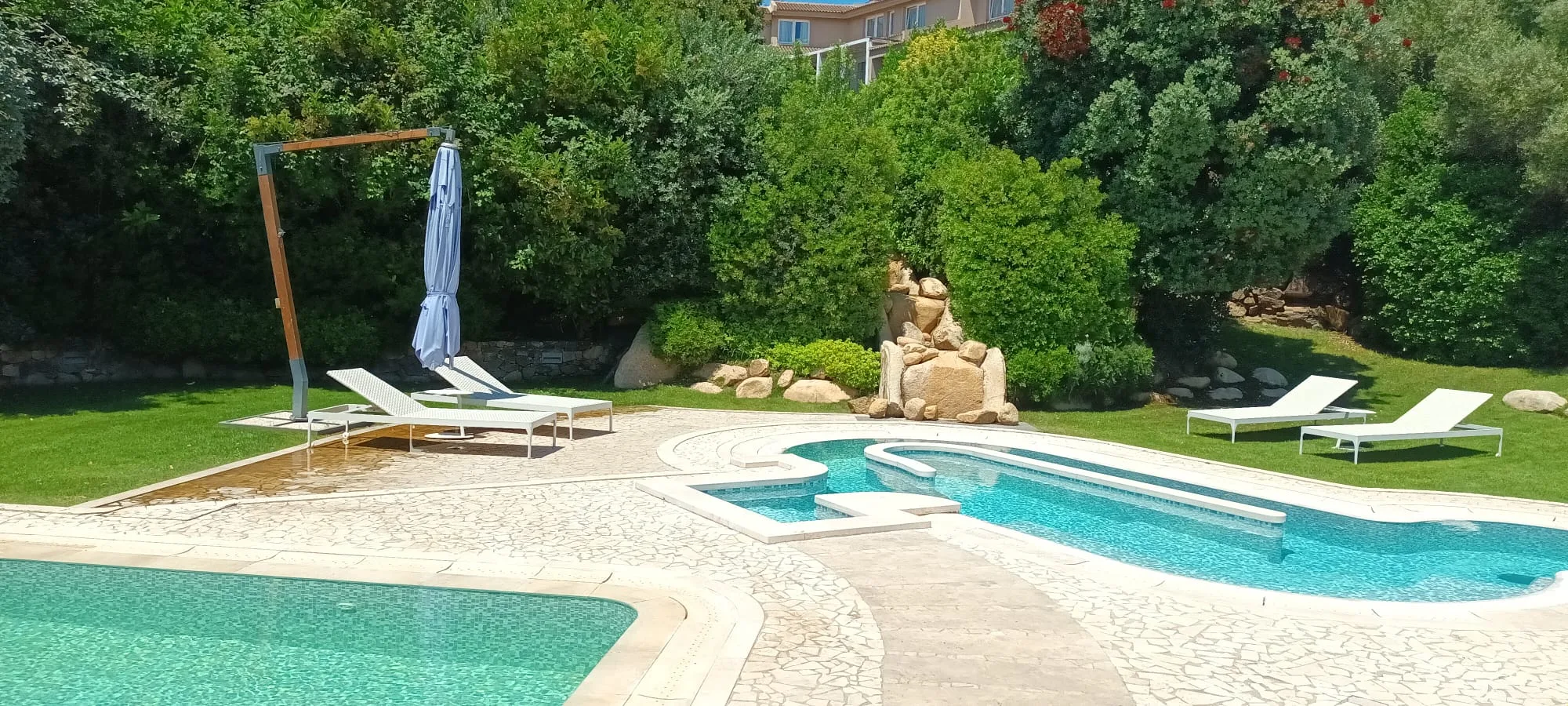 Außenbereich mit Pool und Liegestühlen im Hotel Conrad Chia Laguna auf Sardinien