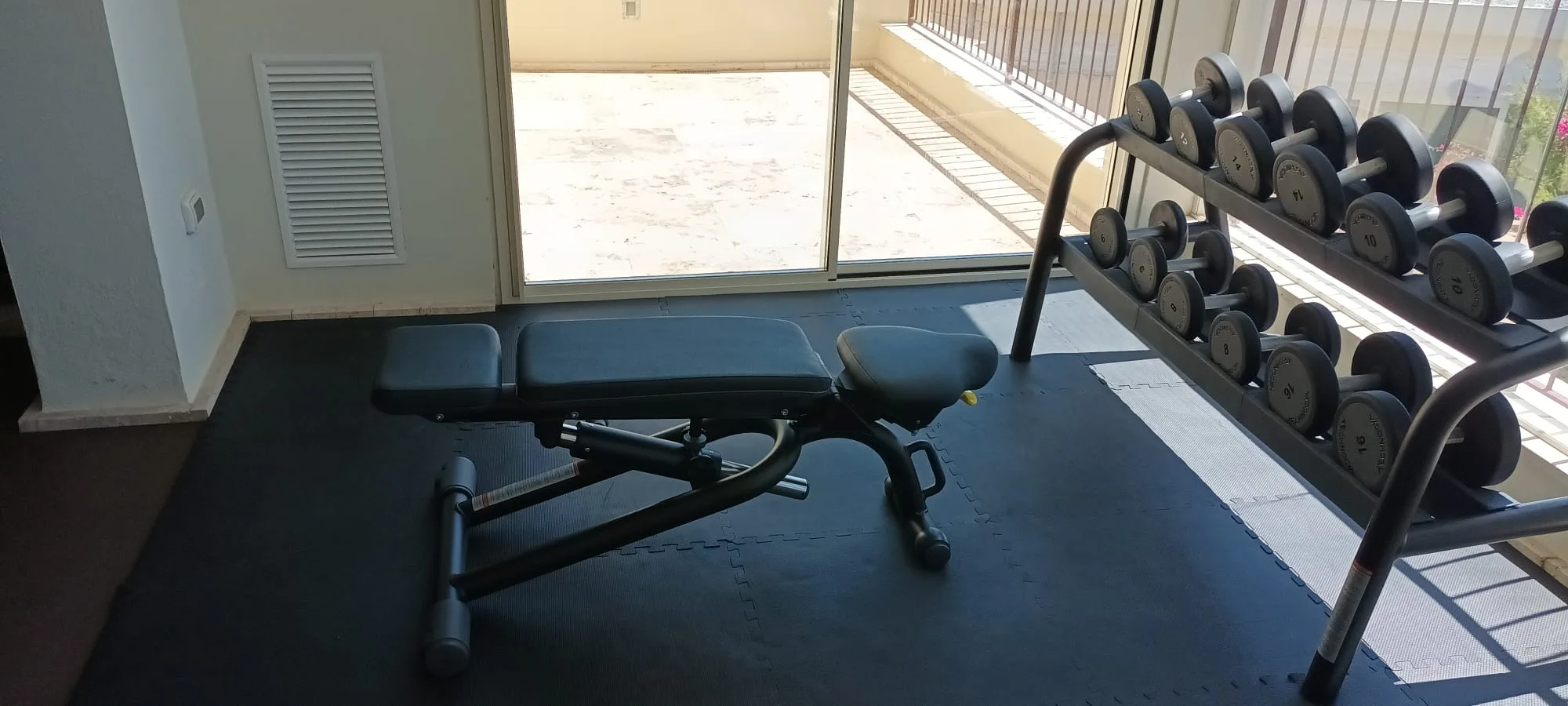 Fitnessgeräte im Hotelgym mit Gewichtsregal und verstellbarem Bankstuhl