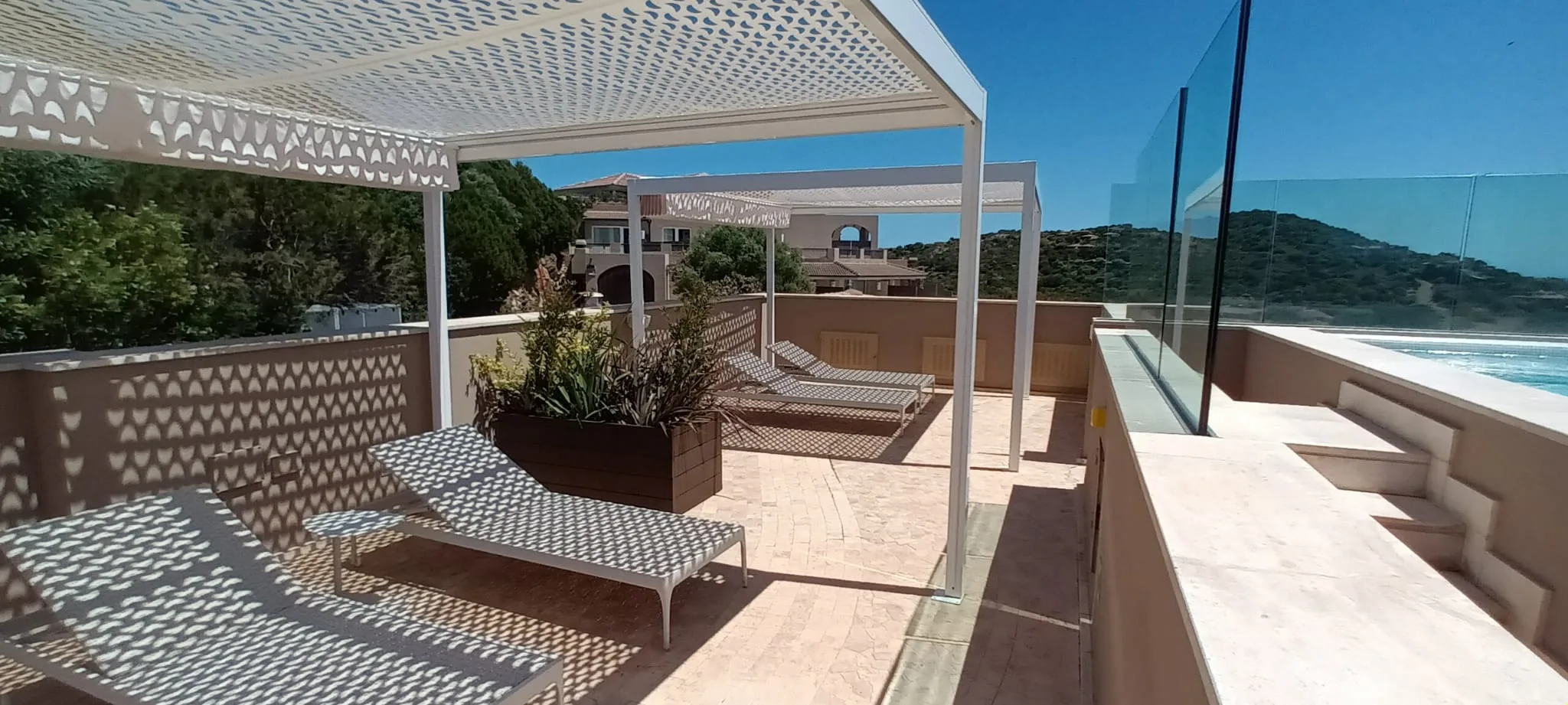 Terrasse mit Liegestühlen und Pflanzenkästen unter Sonnenschutz