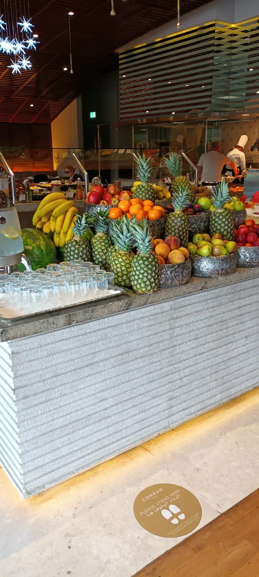 Fruchtschale mit Ananas, Bananen und weiterem Obst auf Frühstückstheke