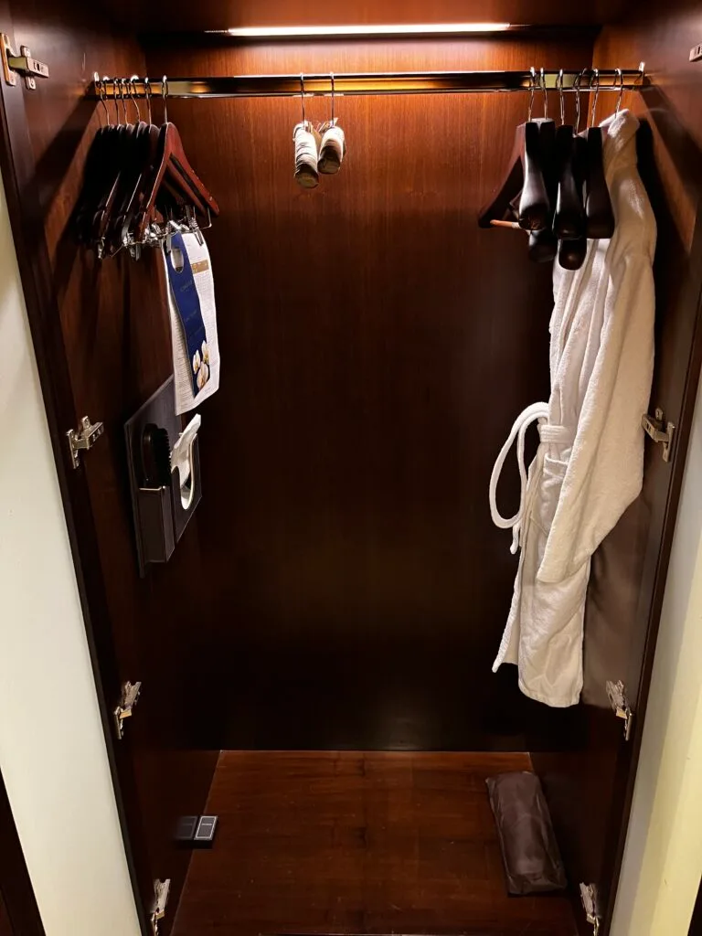 Schrank mit Kleidungsständern und Handtuchhalter im Hotelzimmer