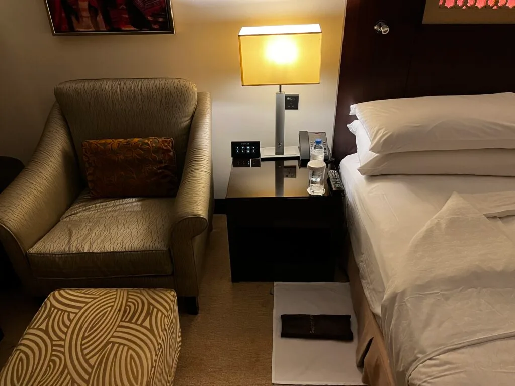 Hotelzimmer mit Doppelbett und Sessel in warmen Farbtönen