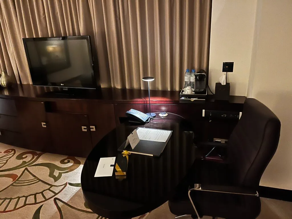 Hotelzimmer mit Schreibtisch, Stuhl und Fernseher
