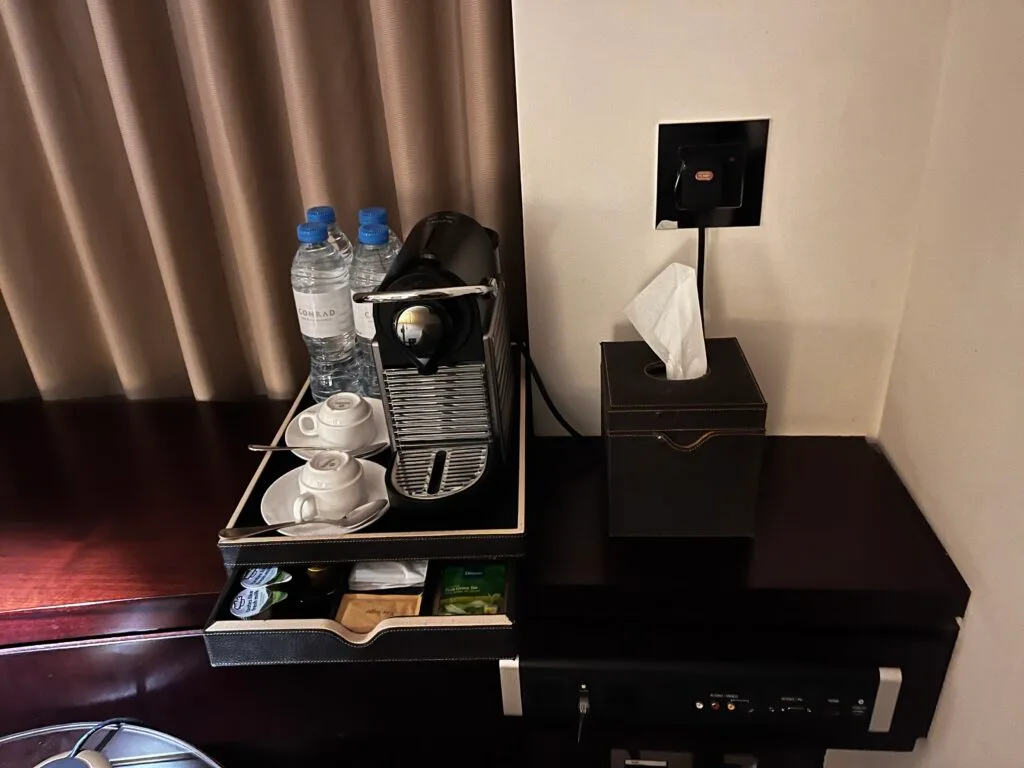 Hotelzimmer mit Kaffeemaschine und Getränken auf Nachttisch