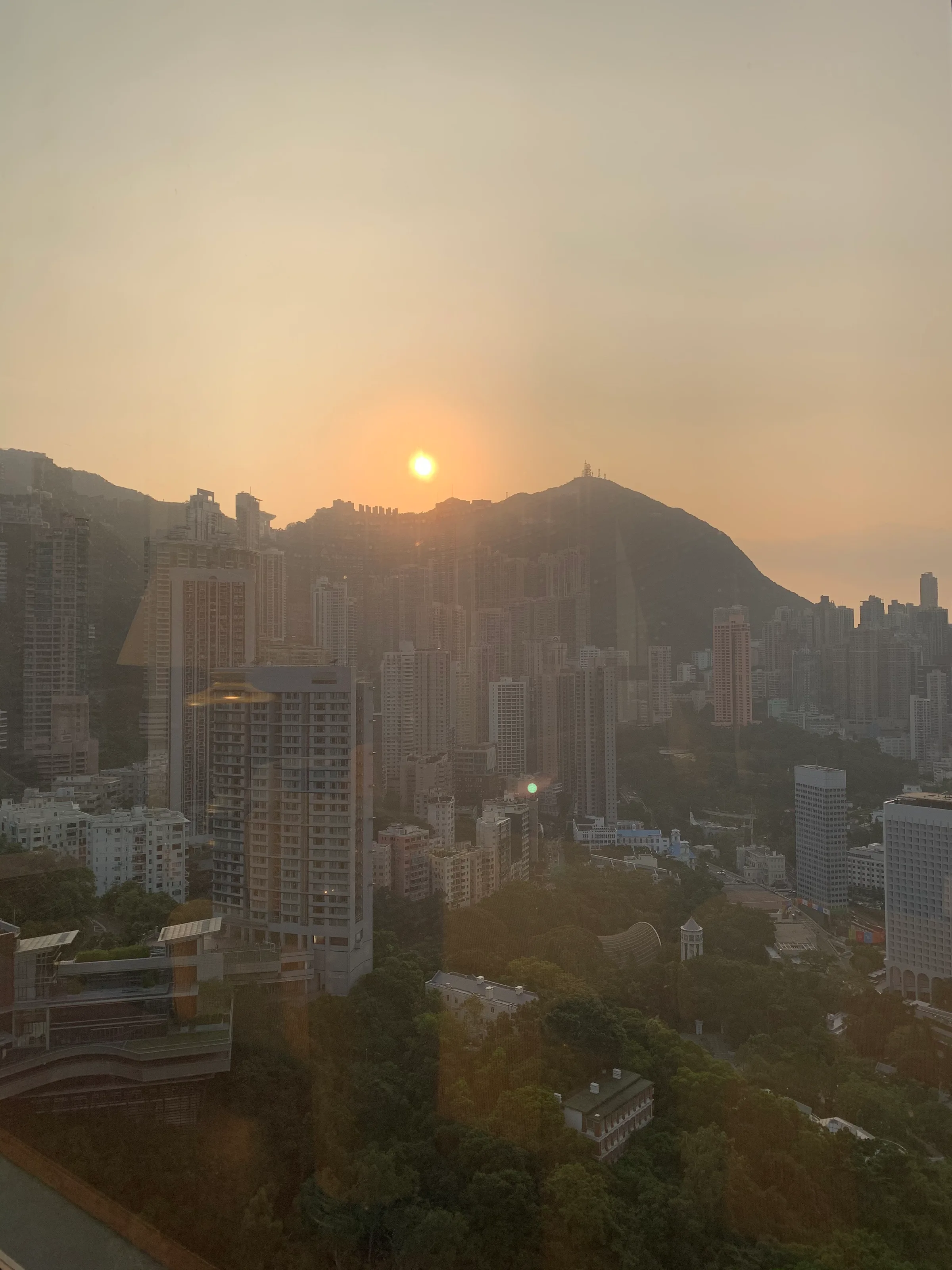 Stadtansicht bei Sonnenuntergang mit Wolkenkratzern und Hügeln im Hintergrund