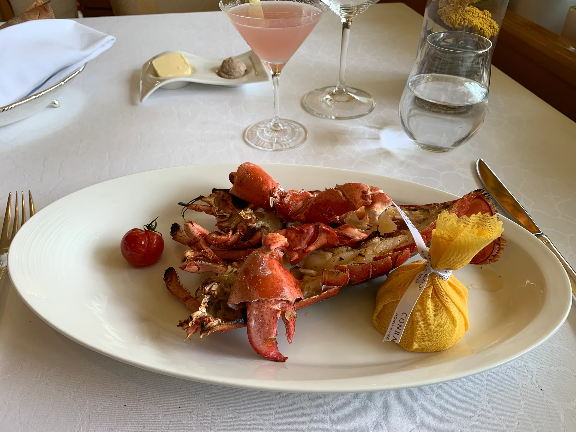 Gegrillter Hummer auf weißem Teller mit Tomate und Butter