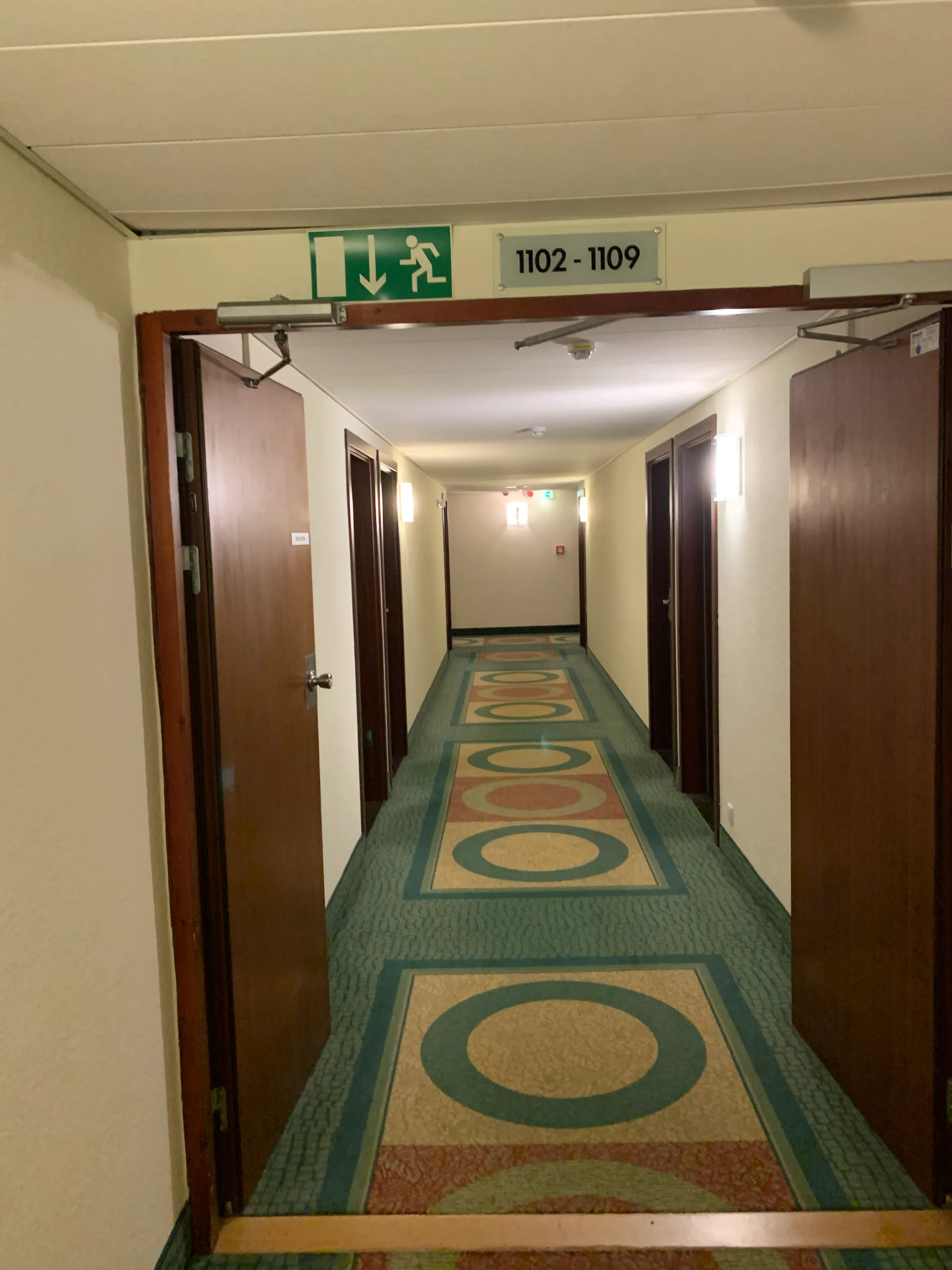 Gang mit Zimmernummernschild und Teppichboden im Hotel