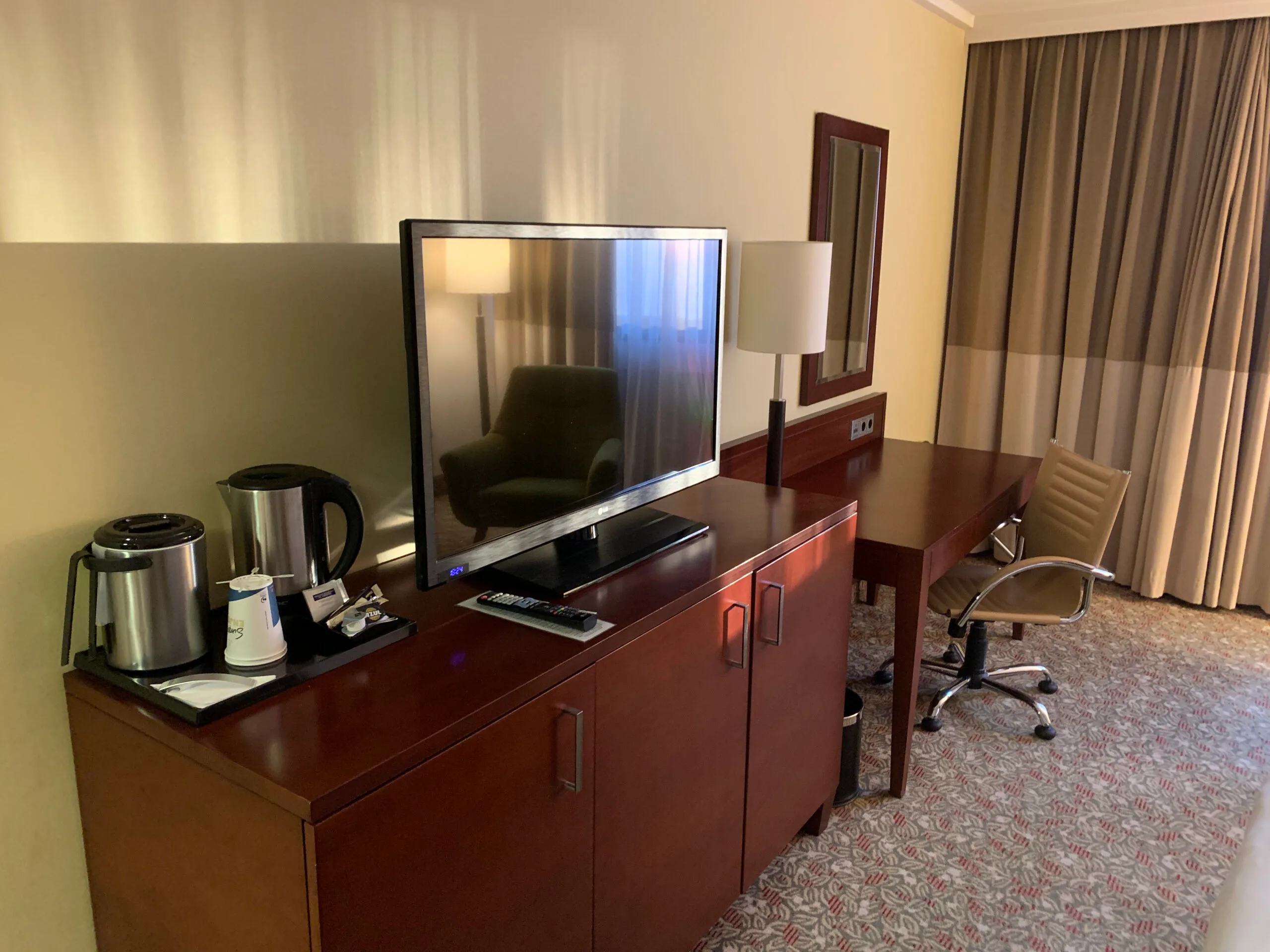 Hotelzimmer mit Fernseher auf Schrank und Schreibtisch