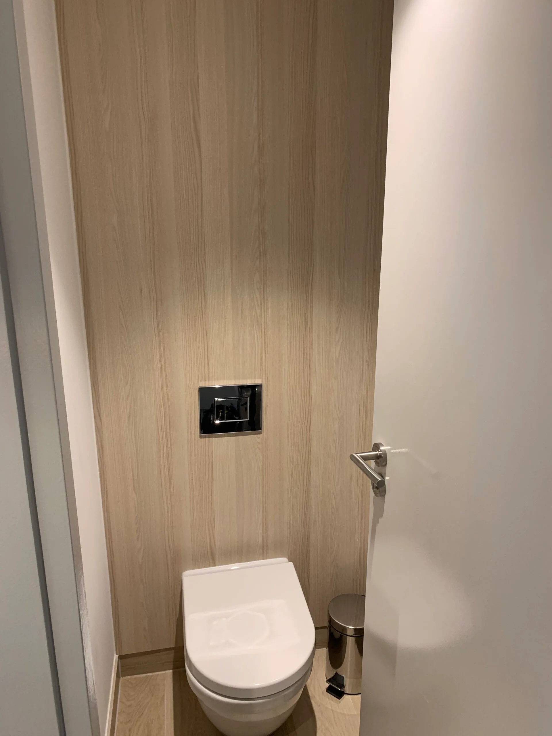 Moderne Toilette mit Holzwand und digitalem Bedienfeld