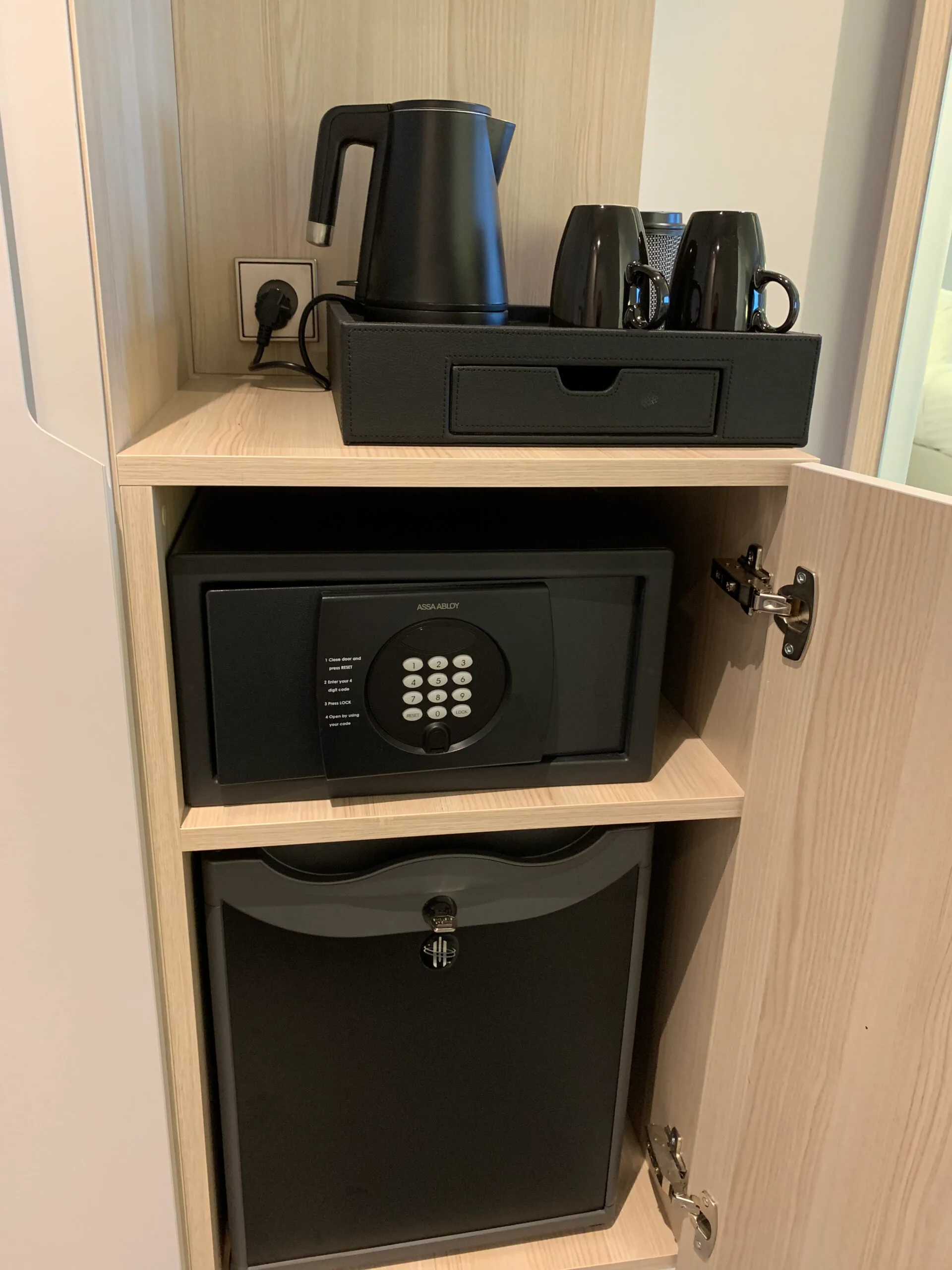 Hotelzimmerschrank mit Kaffeemaschine, Tassen und Safe