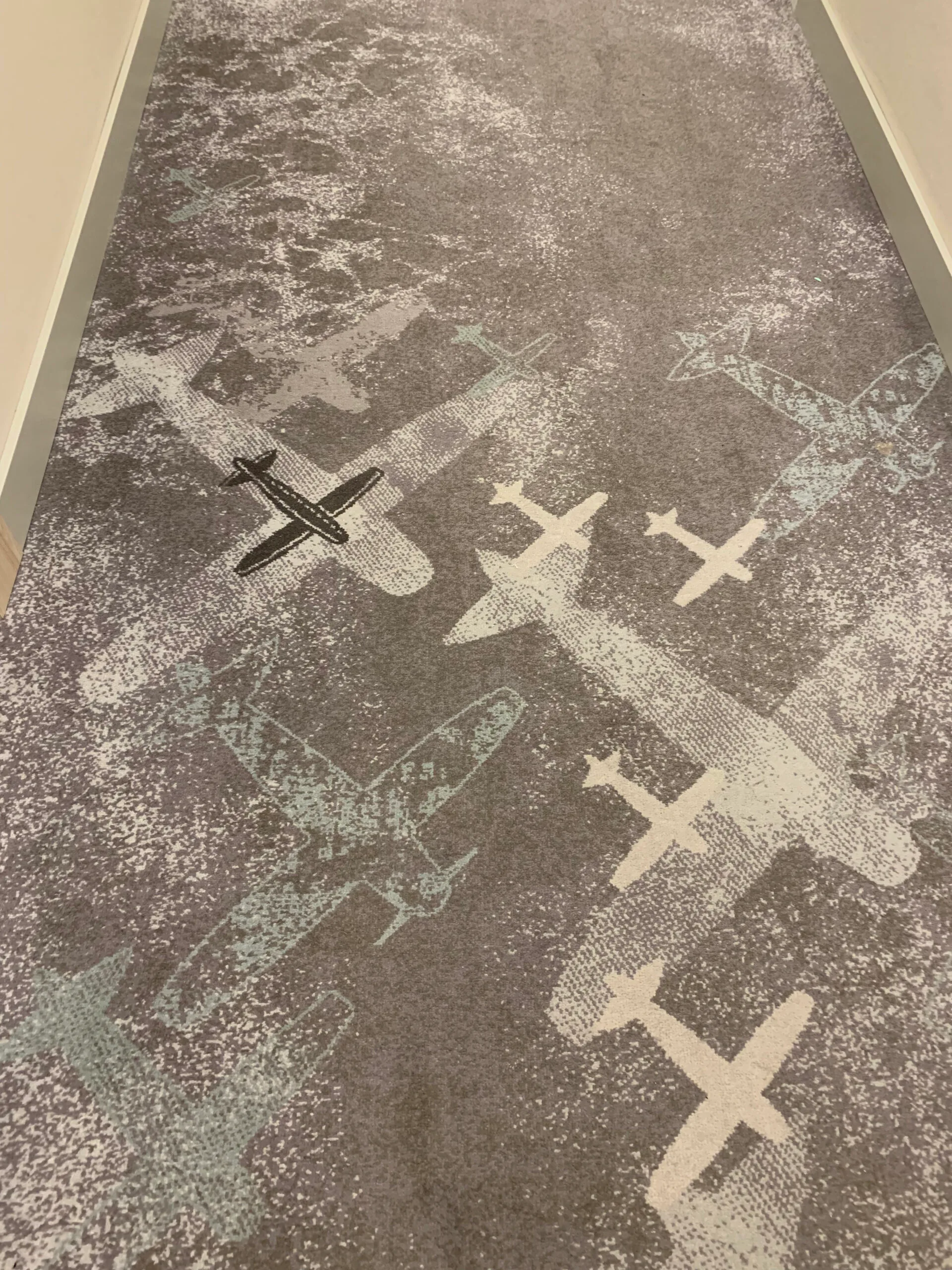 Einzelbett im Hotelzimmer mit grauer Decke und Nachttischlampe