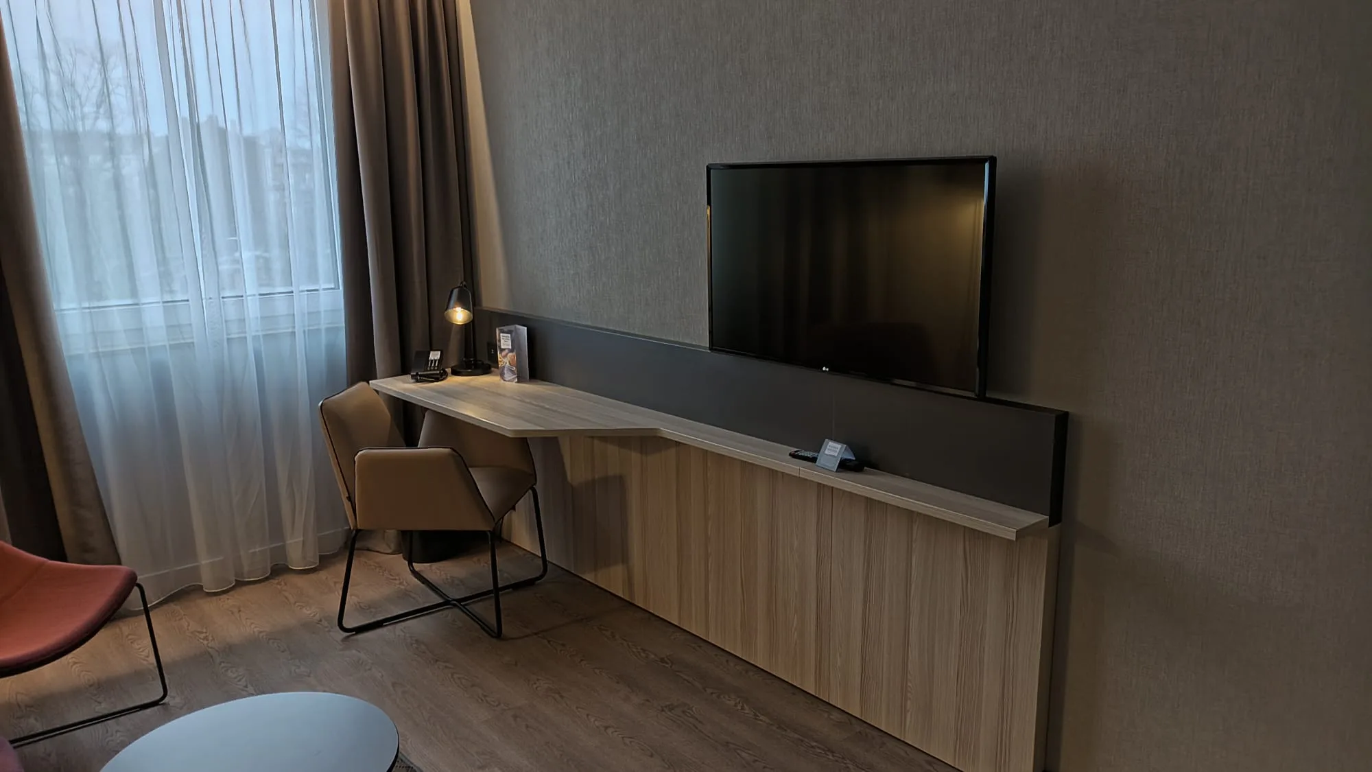 Hotelzimmer mit Schreibtisch und Fernseher an der Wand