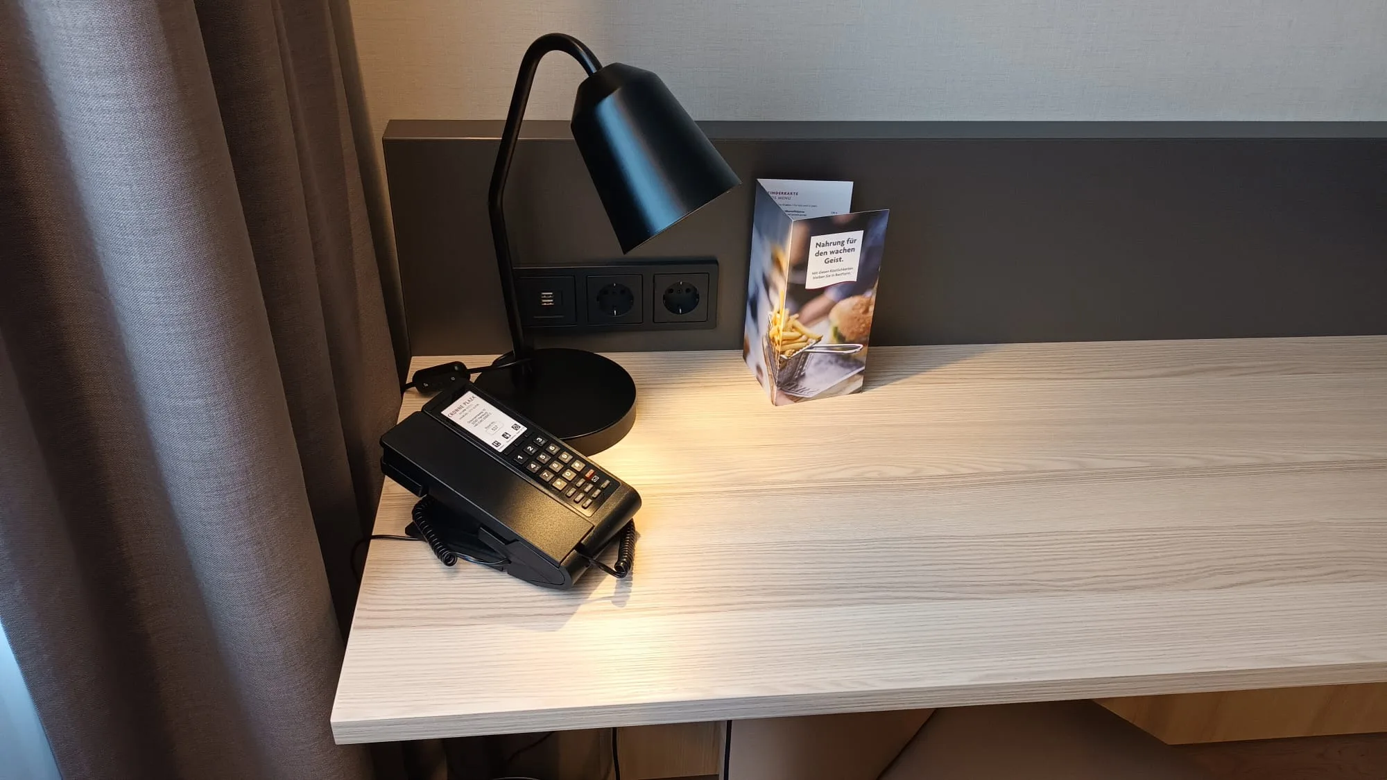 Hotelzimmer mit Schreibtisch, Telefon und Lampenleuchte