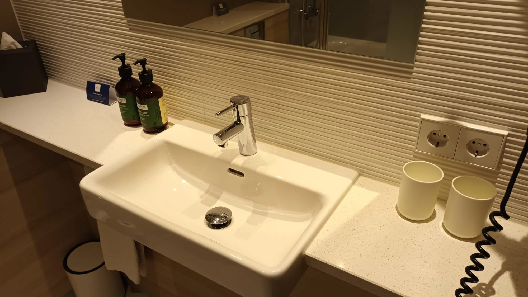 Moderne Waschtisch im Hotel mit Spiegel und Kosmetikflaschen