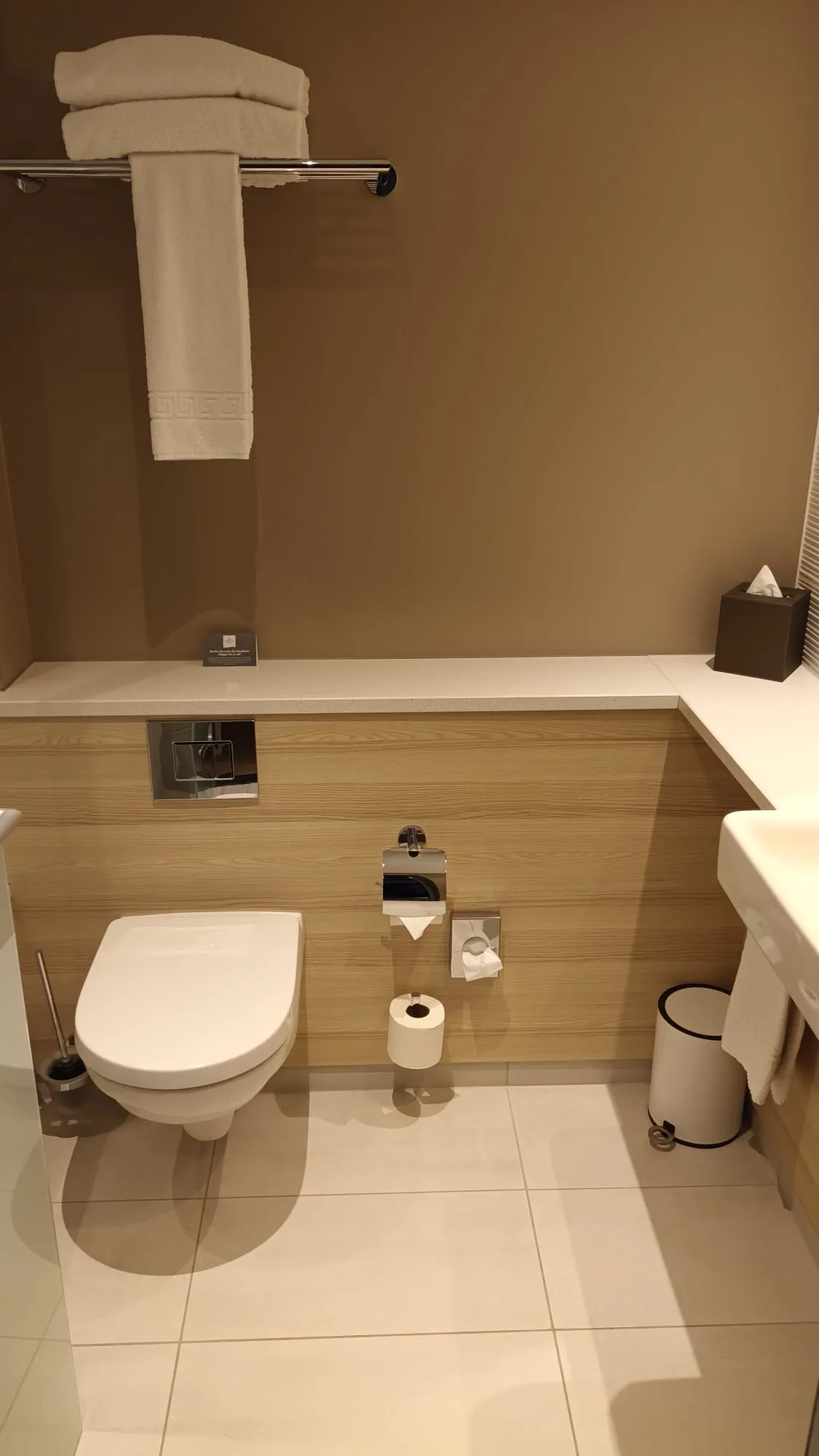 Moderne Toilette mit Holzverkleidung und Handtuchhalter