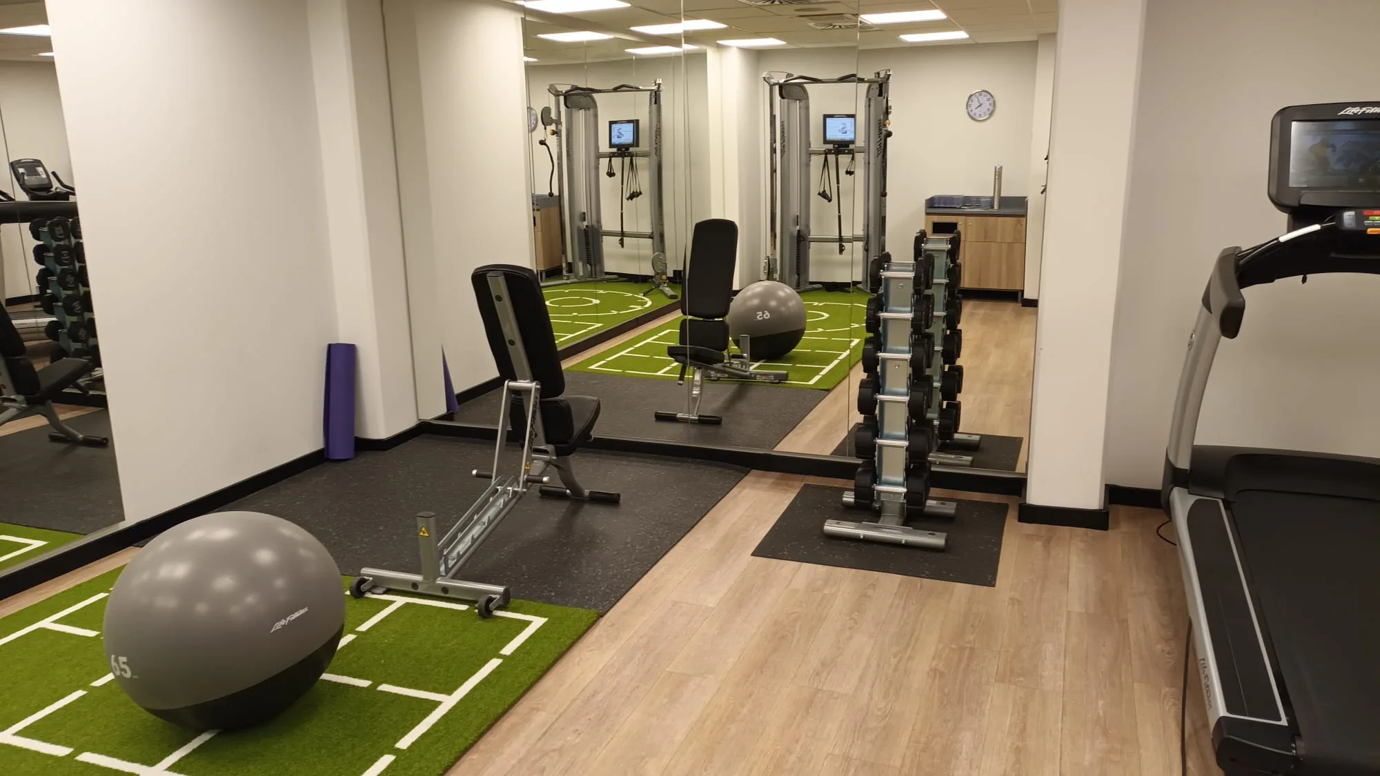Fitnessraum mit Trainingsgeräten und Spiegeln