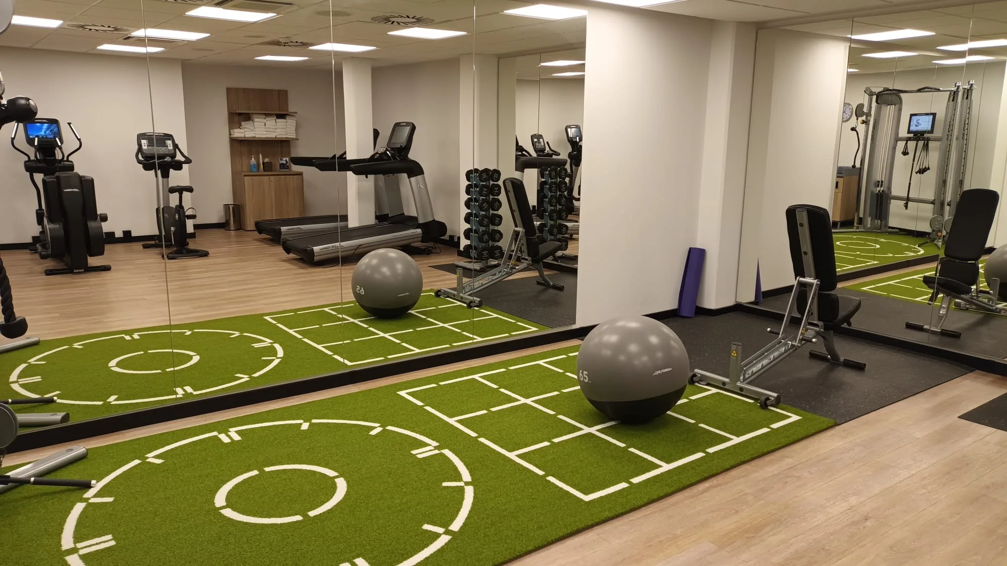 Fitnessraum mit Spiegeln, Trainingsgeräten und Trainingsballen