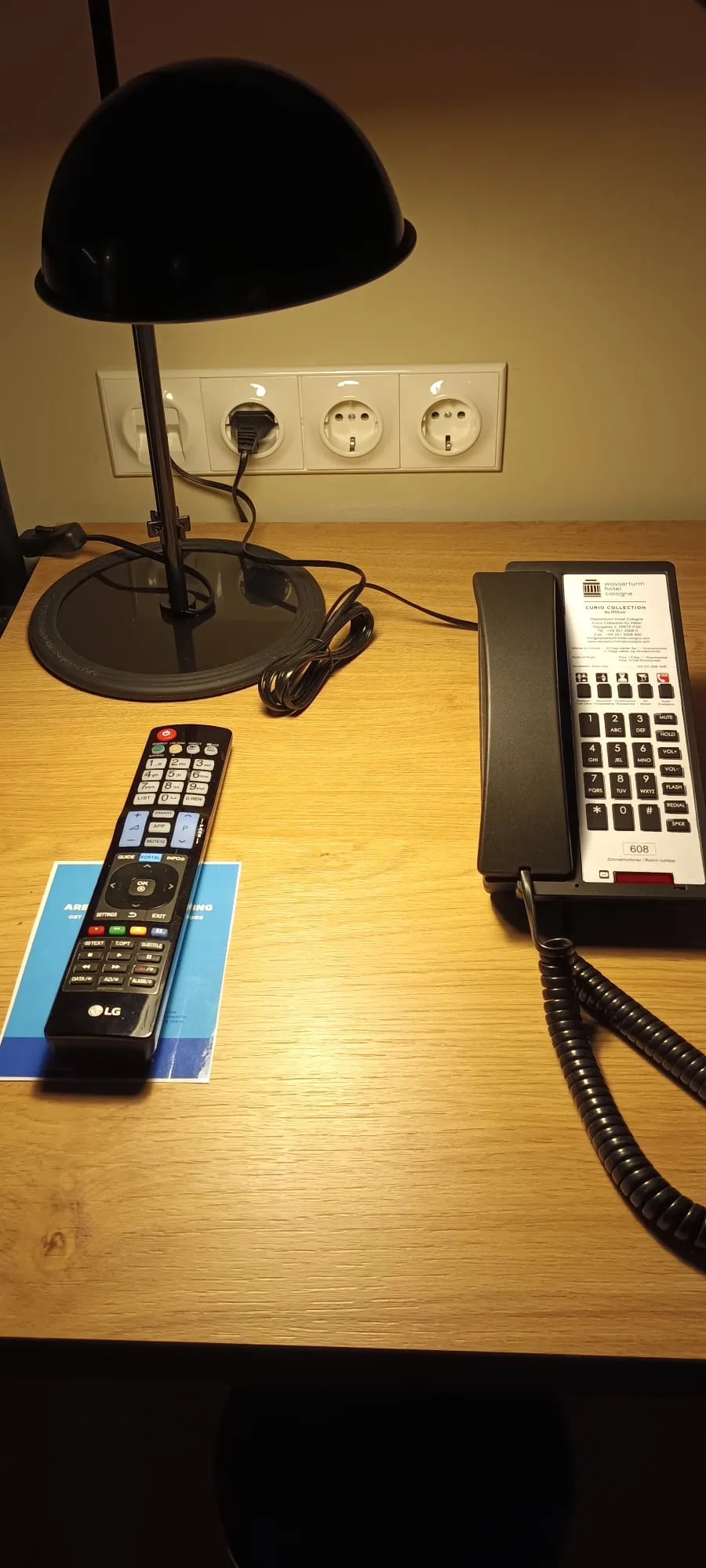 Hotelzimmer mit Tischlampe, Fernbedienung und Telefon