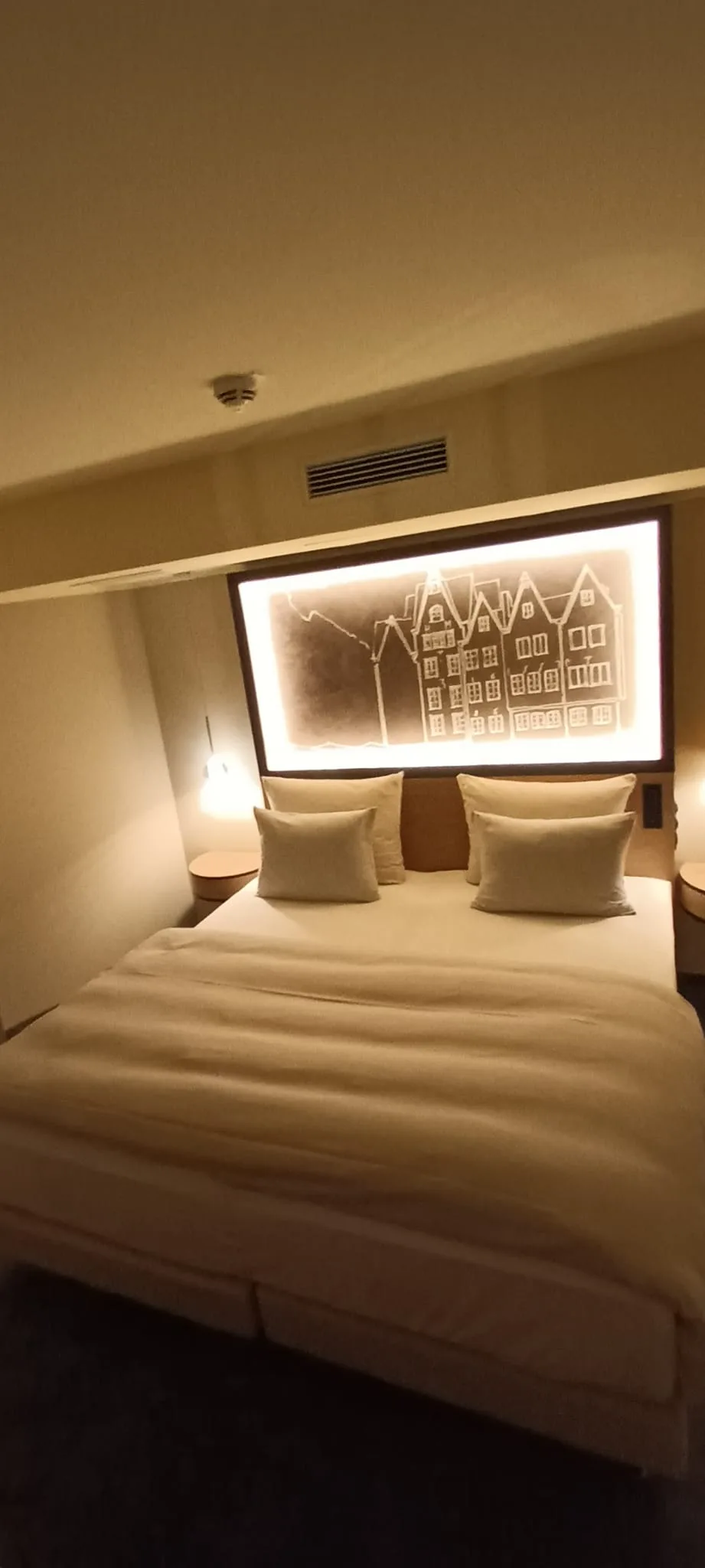 Doppelbett im Hotelzimmer mit beleuchteter Wanddekoration