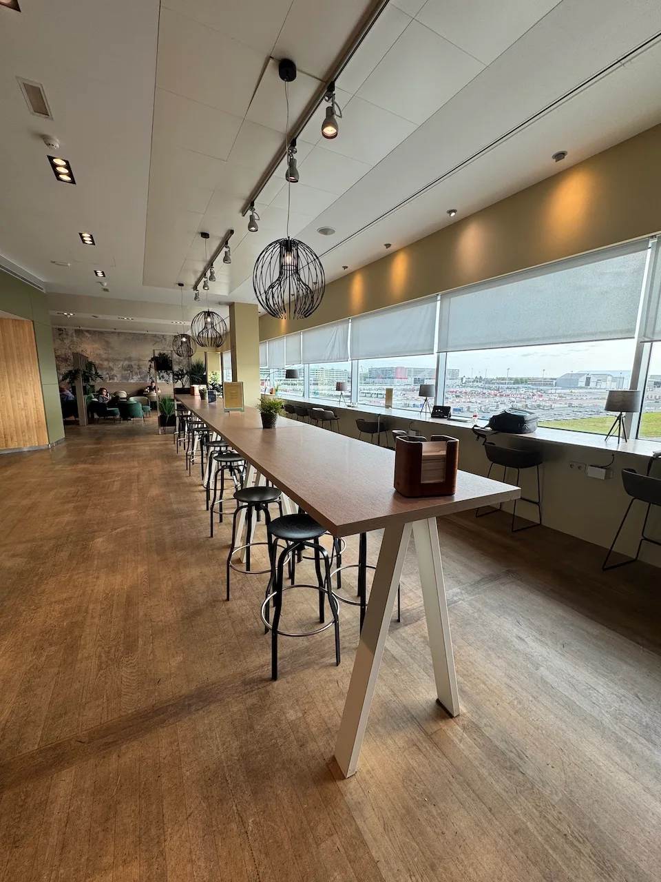 Lounge mit langem Tisch und Stühlen, Blick auf Flughafen