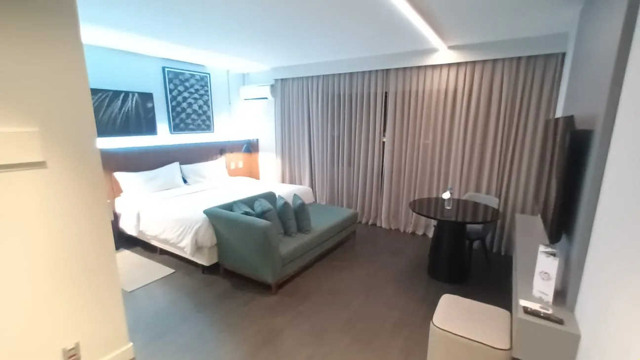 Hotelzimmer mit Doppelbett und Sitzbank in Grautönen