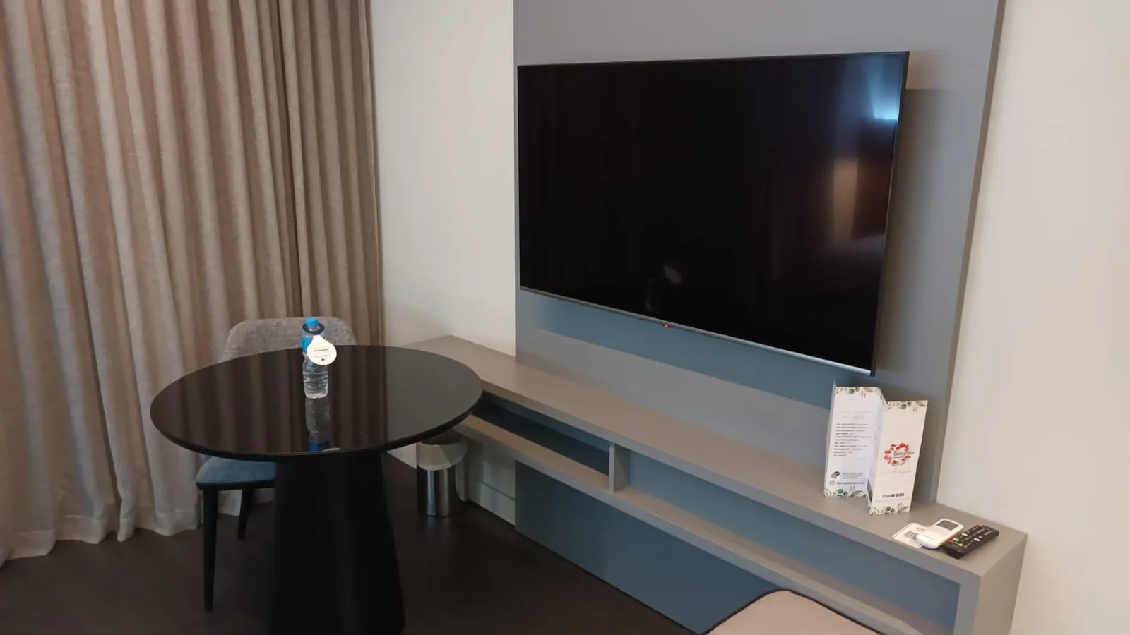 Hotelzimmer mit Tisch und Fernseher an der Wand