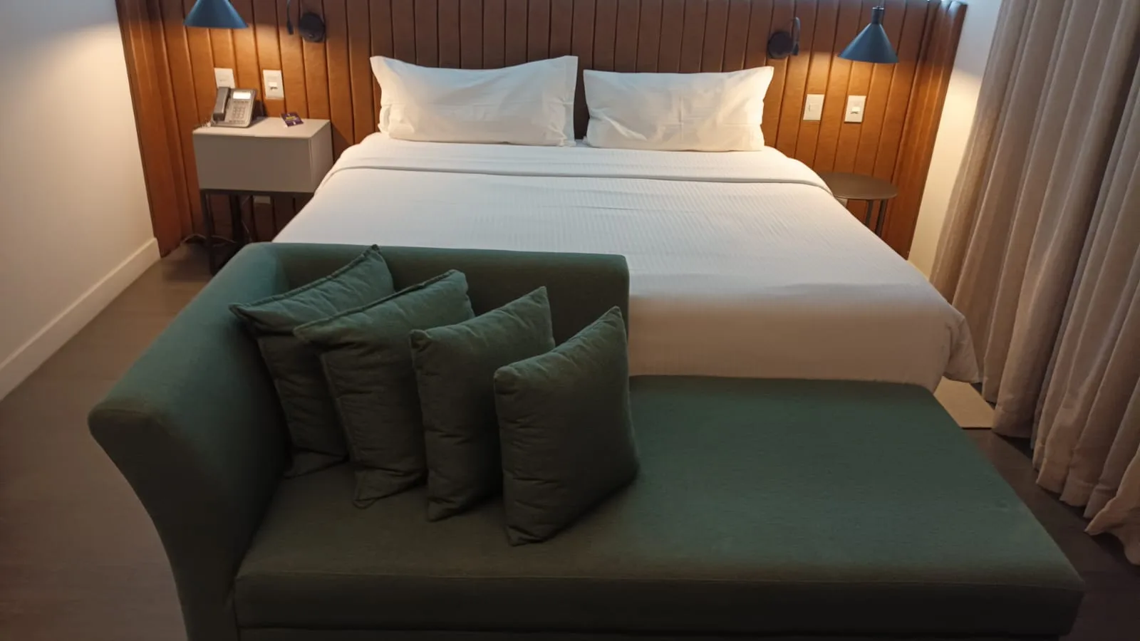 Hotelzimmer mit Doppelbett und grüner Bank