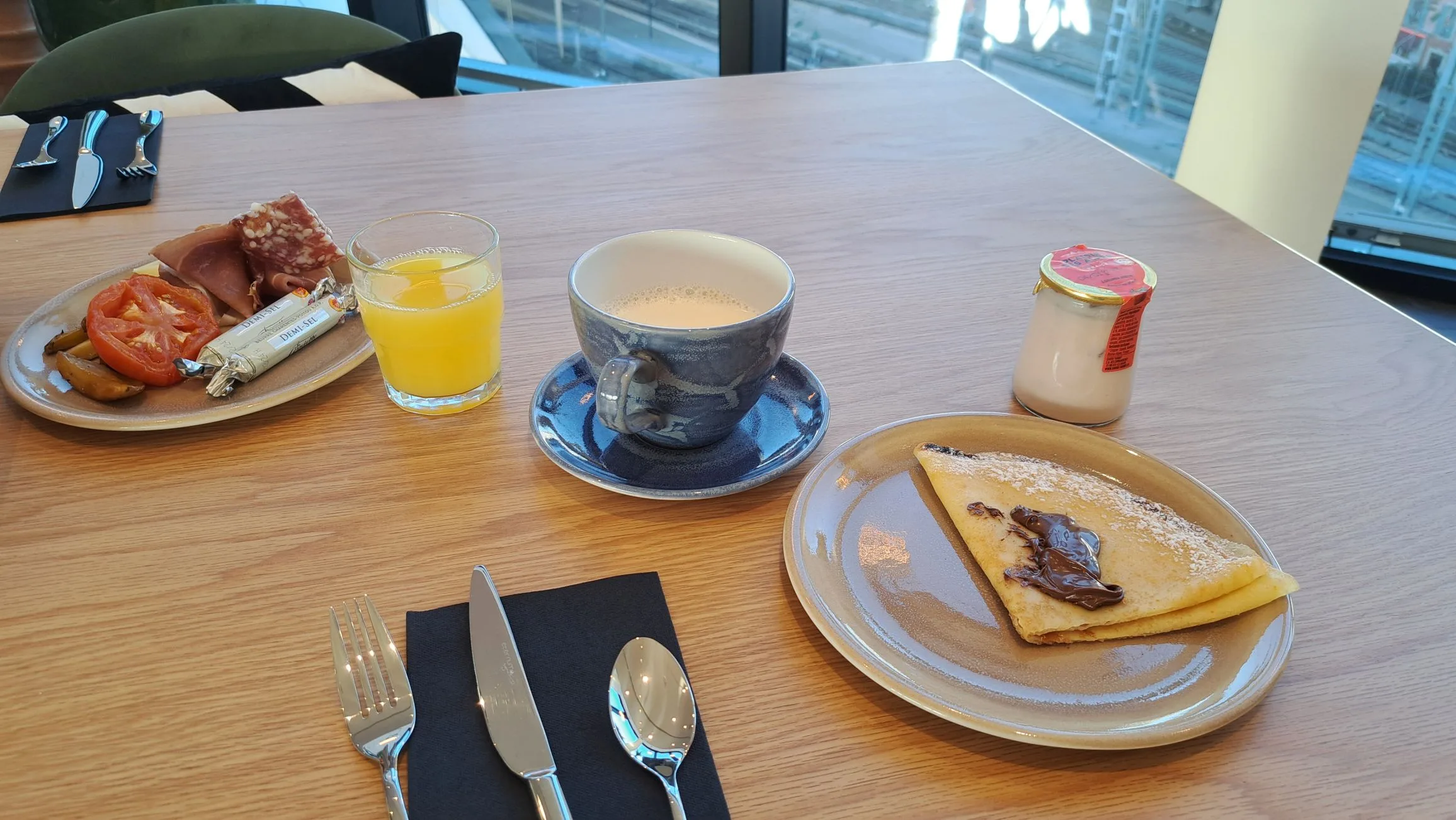 Frühstückstablett mit Kaffee, Orangensaft, Käse und Wurst auf Holztisch