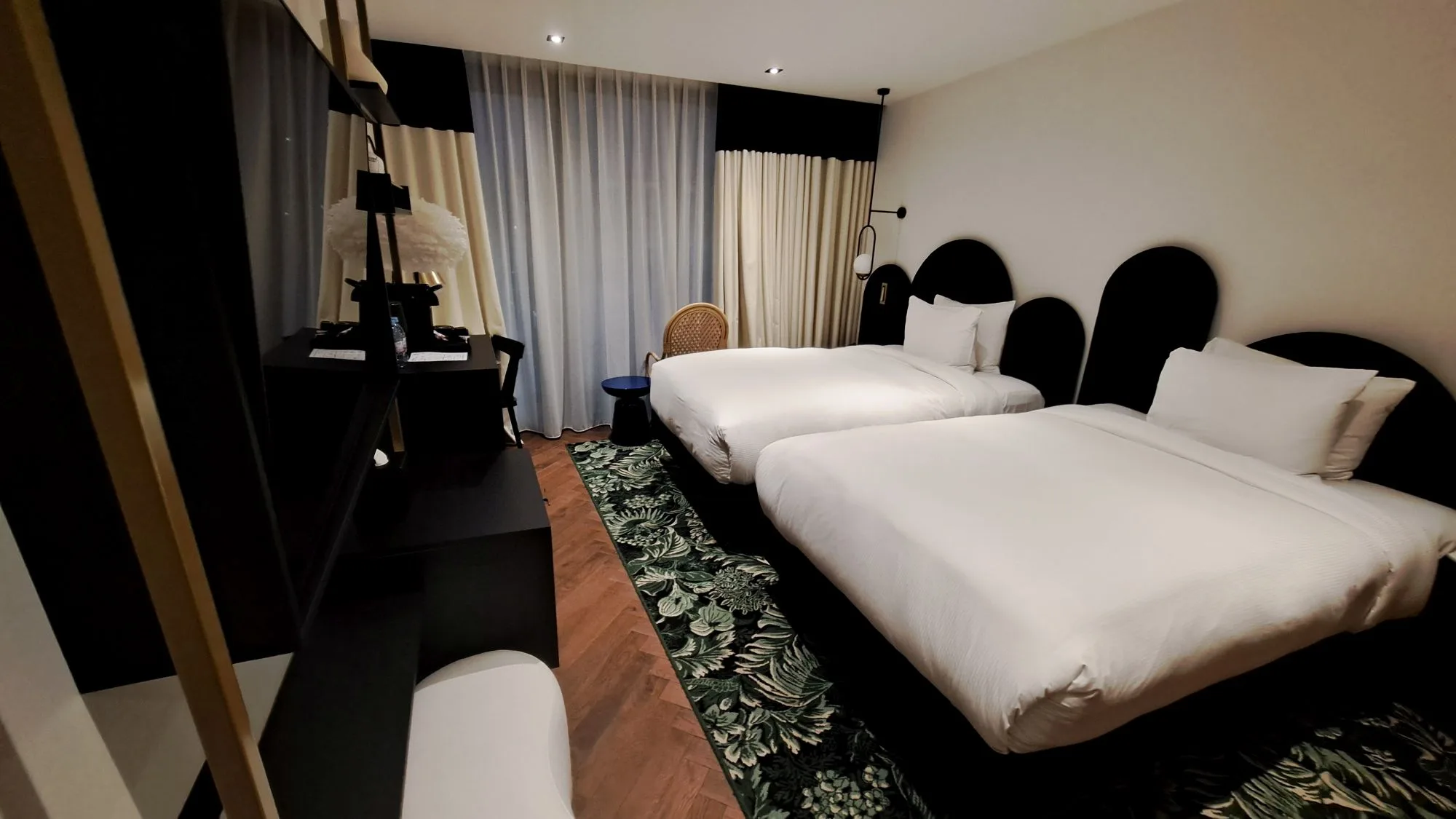 Hotelzimmer mit zwei Einzelbetten und grauen Vorhängen