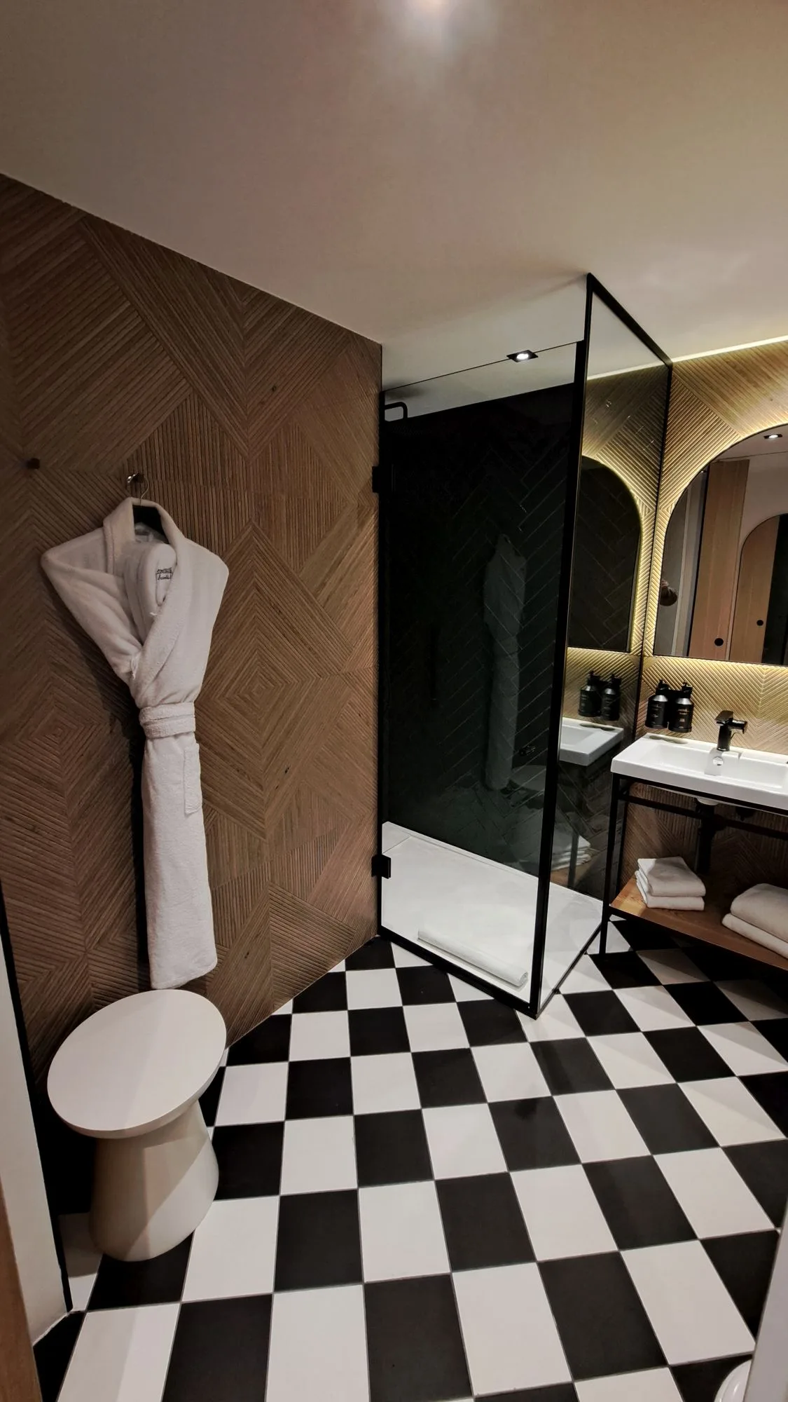 Moderne Badezimmer mit Holzwand und schwarz-weißem Fliesenboden