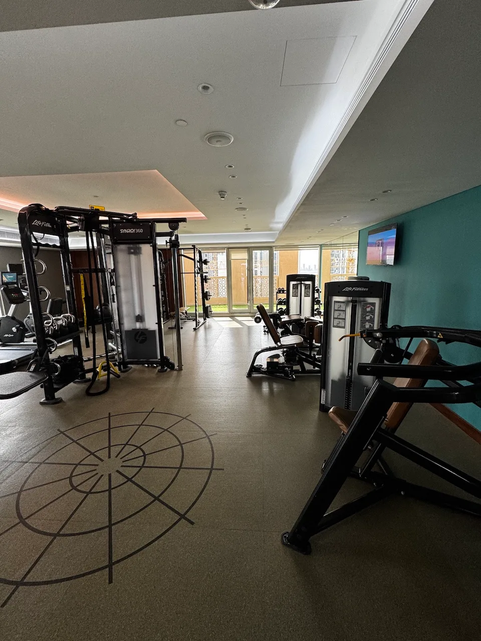 Fitnessraum mit verschiedenen Trainingsgeräten und Bodenmarkierung