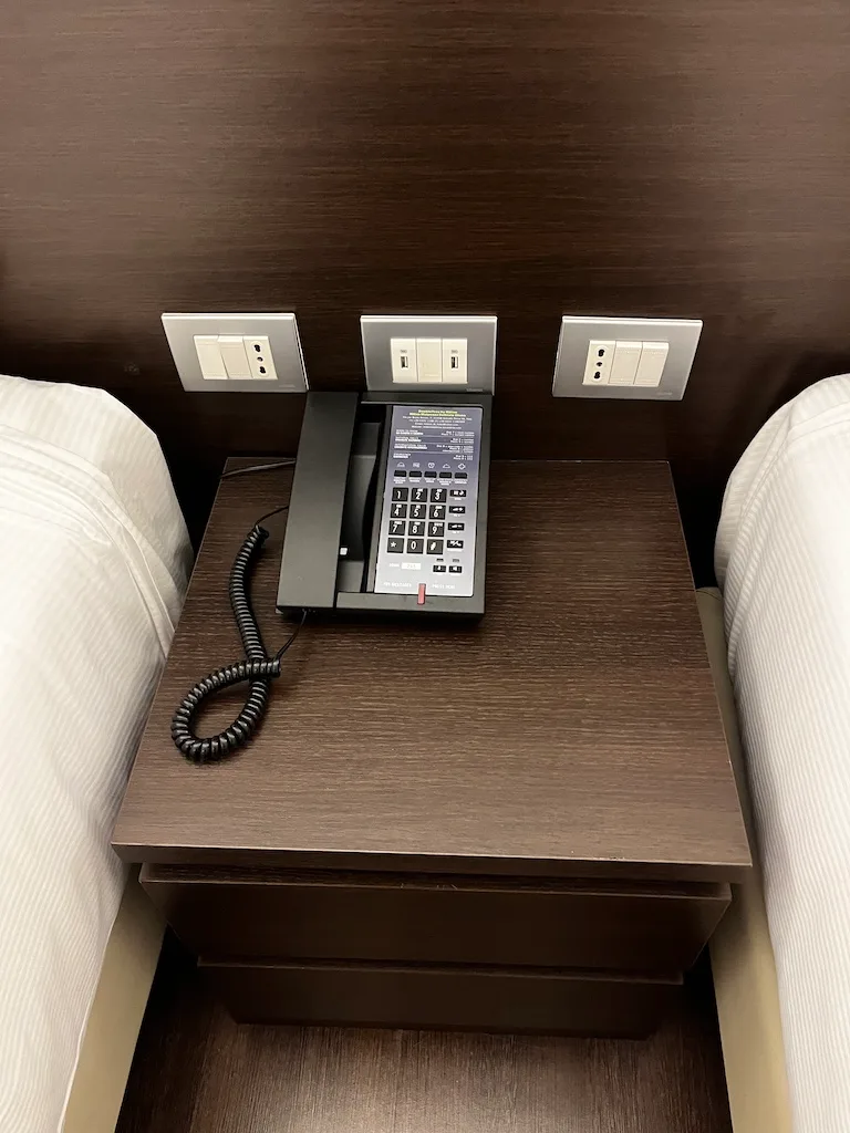Hotelnachttisch mit Telefon und Steckdosen