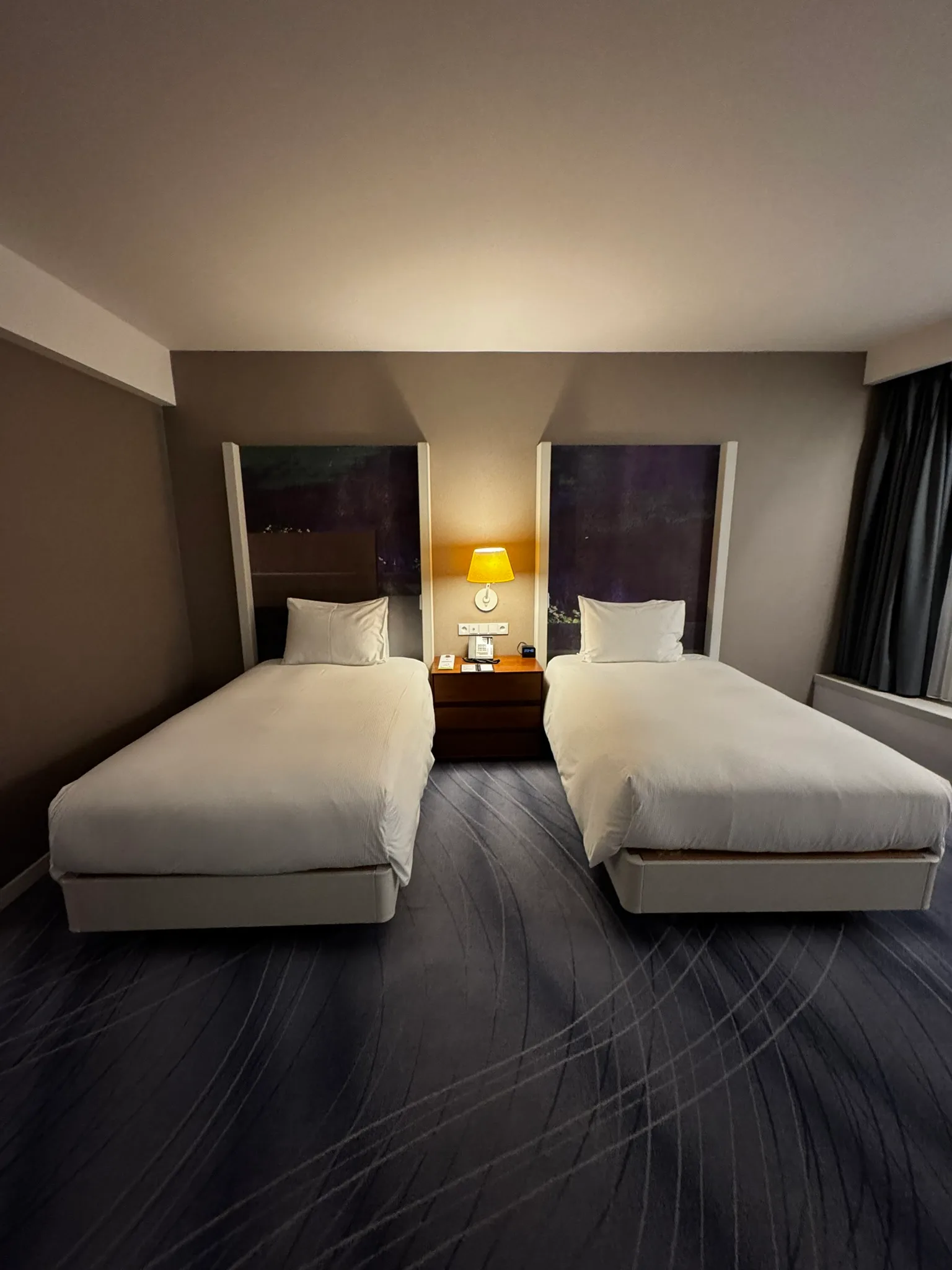 Hotelzimmer mit zwei Einzelbetten und Nachttischlampe