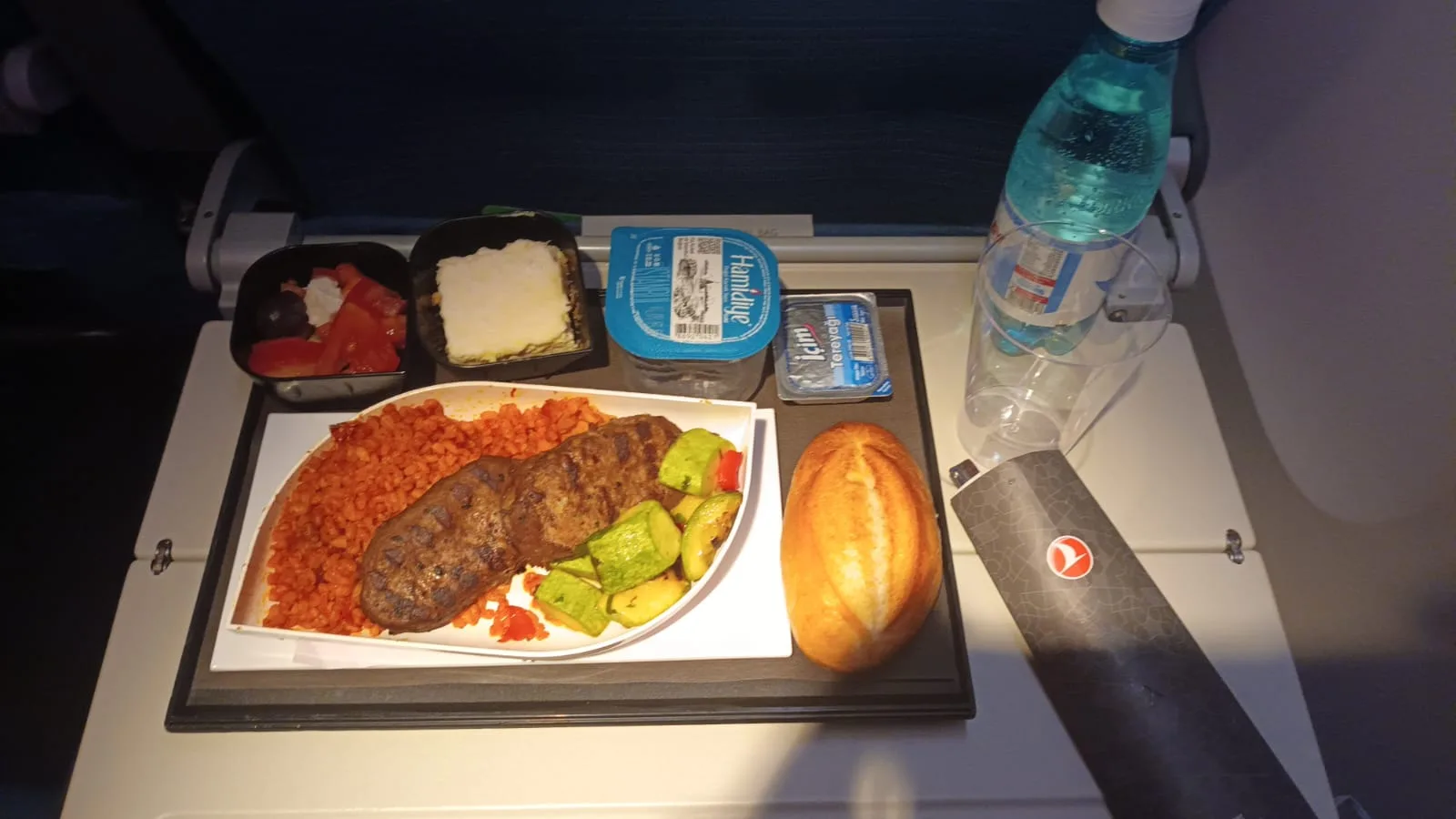 Essensplatte mit Steak, Reis, Gemüse und Brot auf einem Flugzeugtisch