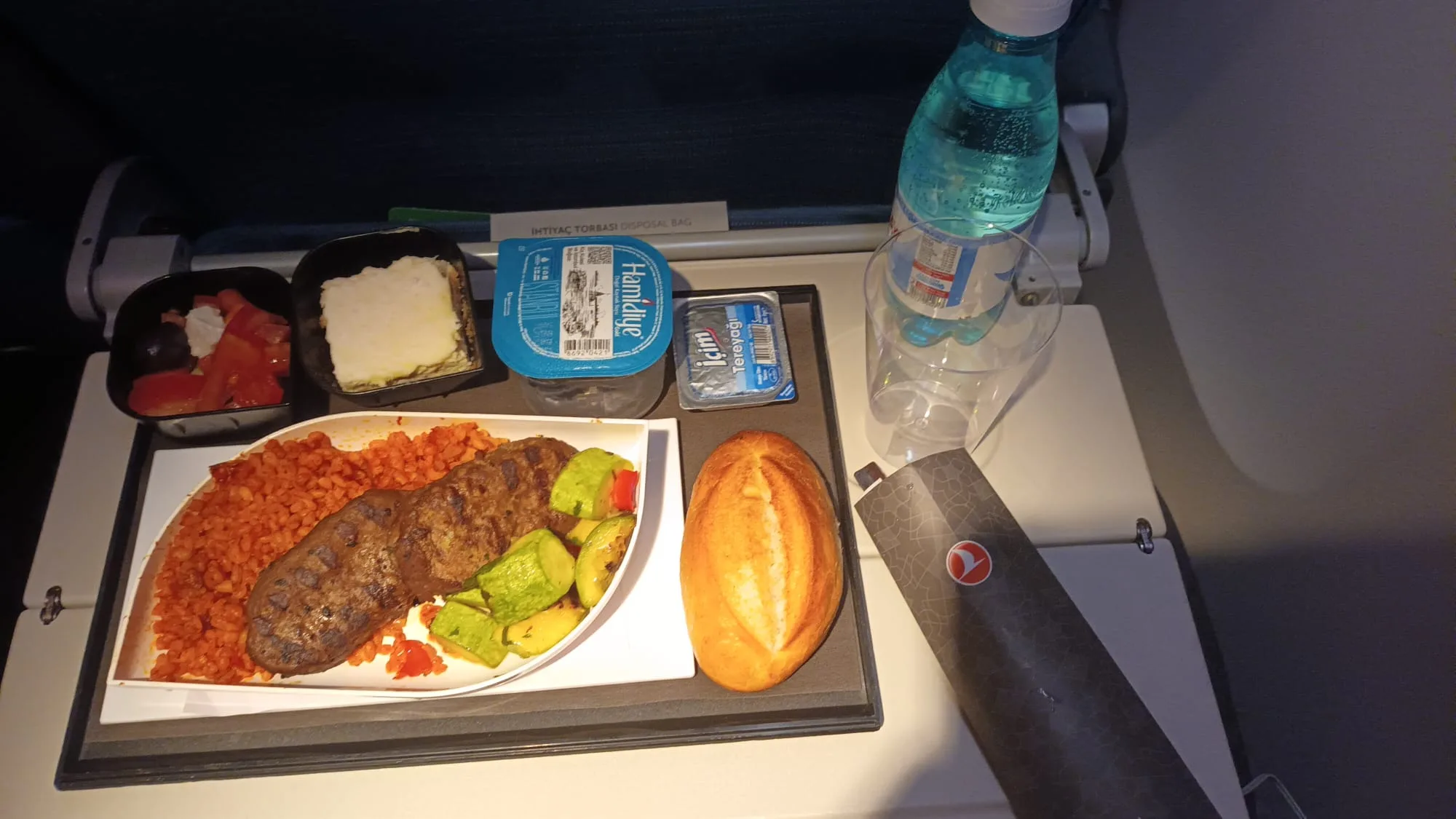Essensplatte mit Fleisch, Gemüse und Brot auf Flugzeugtisch