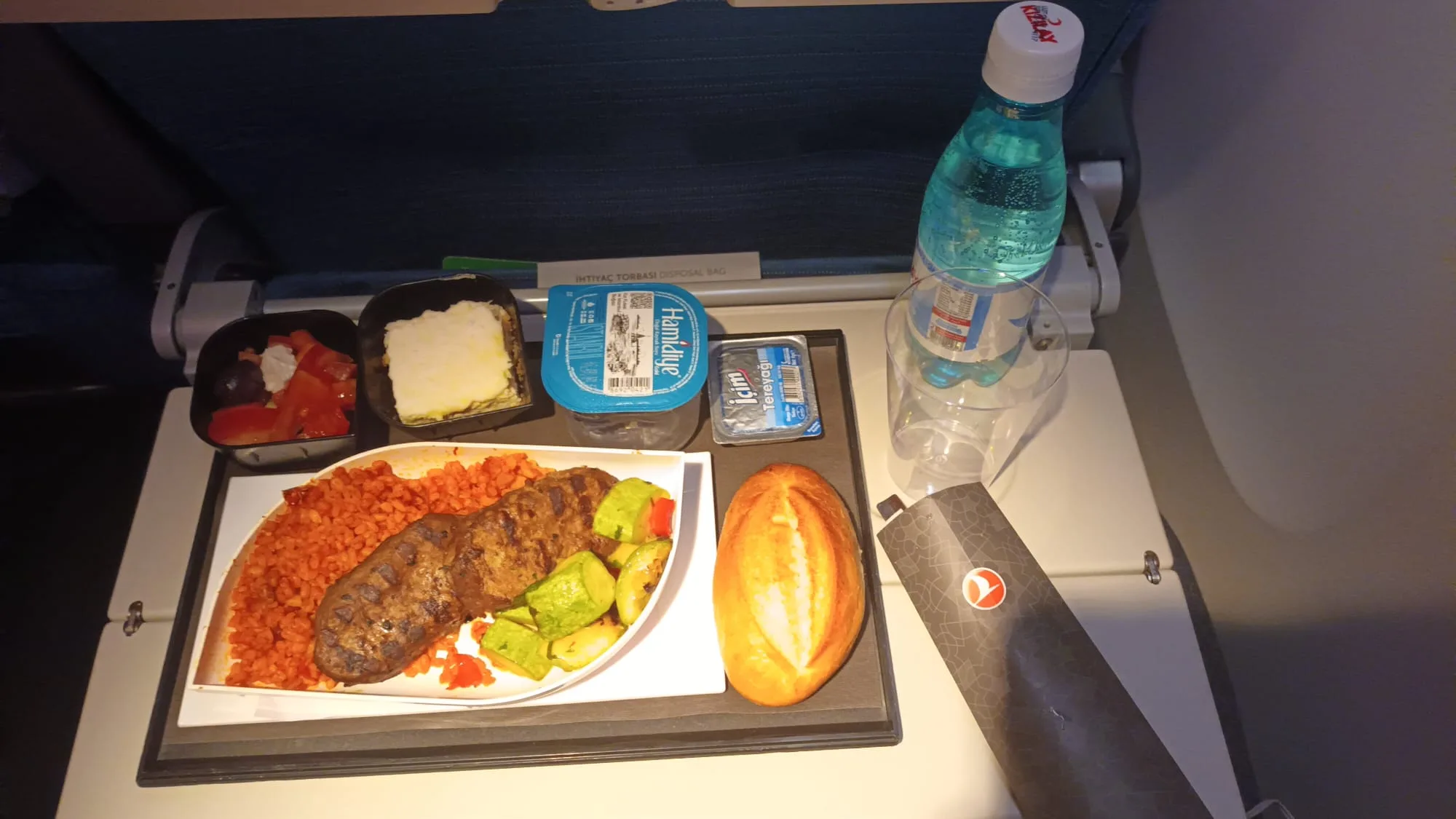 Essensplatte mit Fleisch, Gemüse und Brot auf Flugzeugtisch