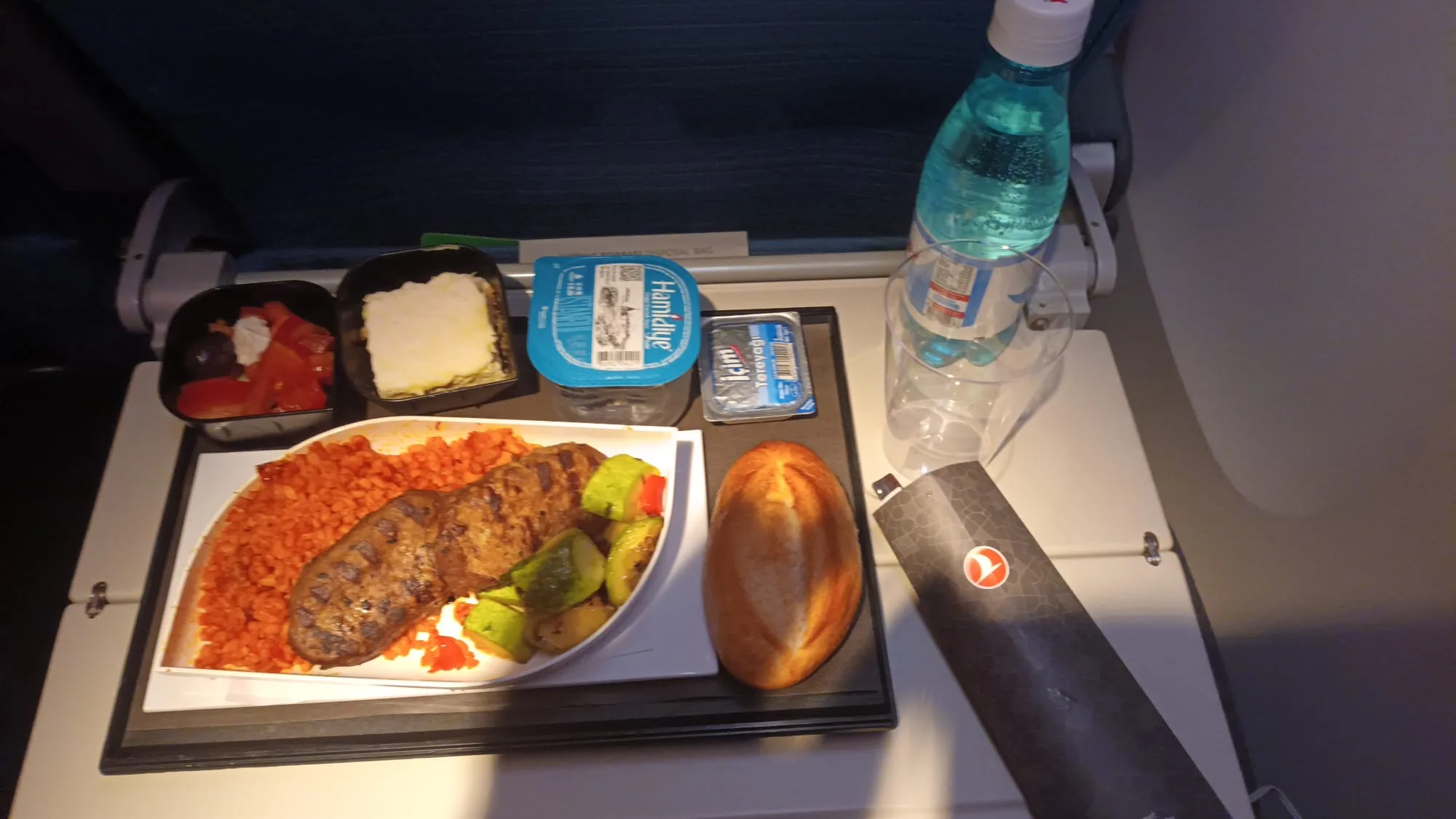 Essensplatte mit Fleisch, Gemüse und Brot auf einem Flugzeugtisch