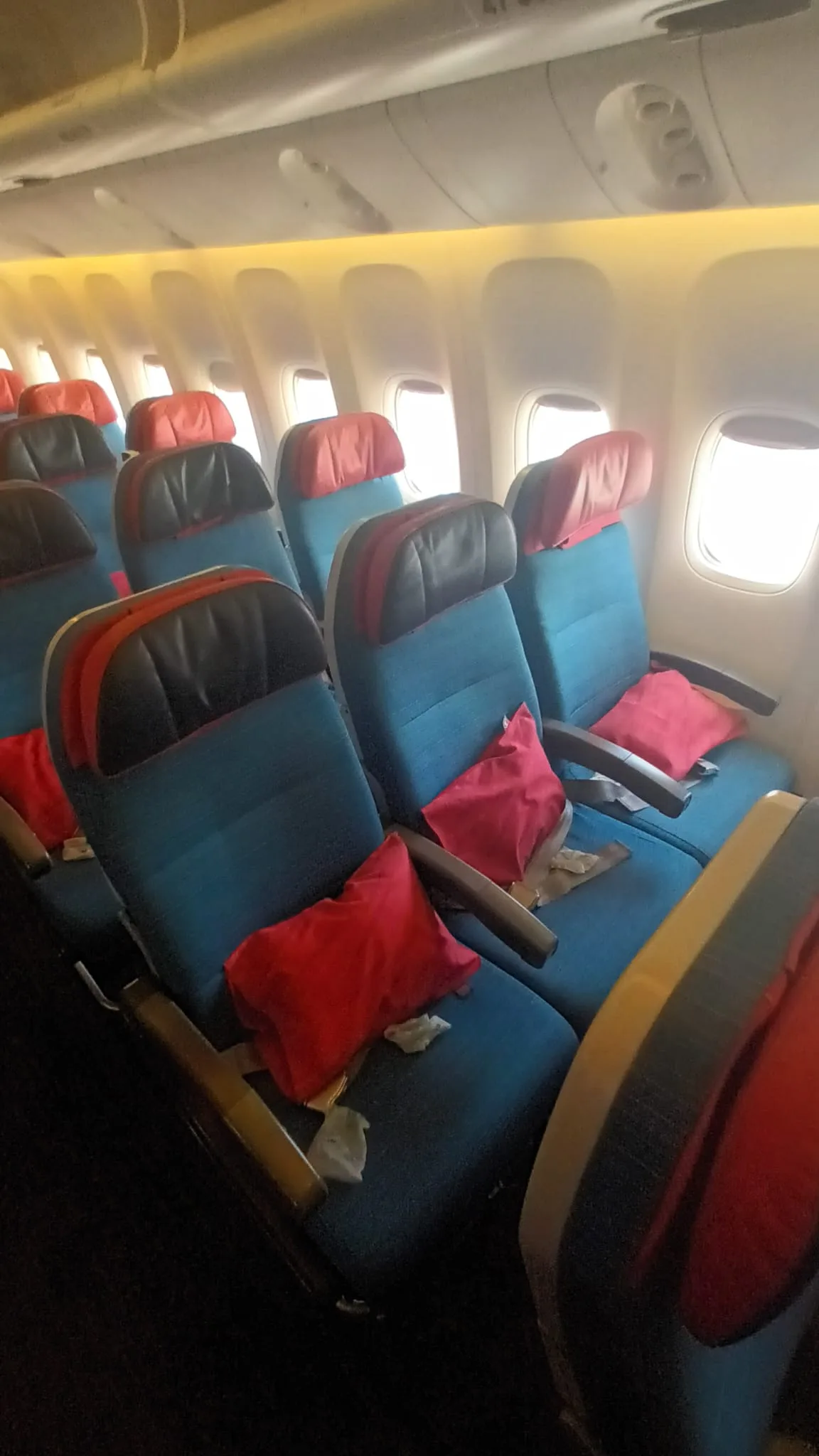 Innenraum eines Flugzeugs mit blauen Sitzen und roten Kissen