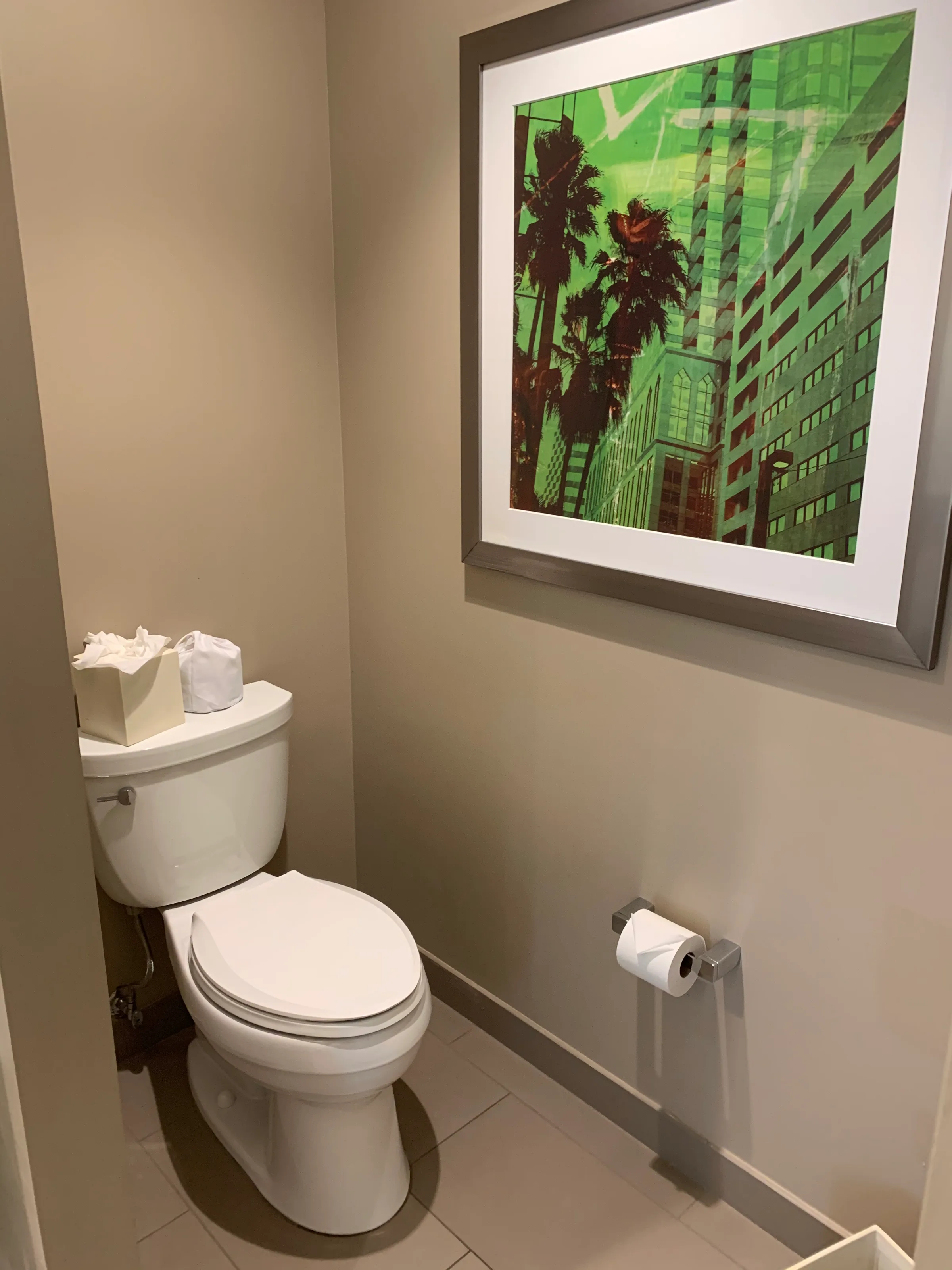 Hotel-WC mit Toilette und Toilettenpapierhalter sowie Kunst an der Wand