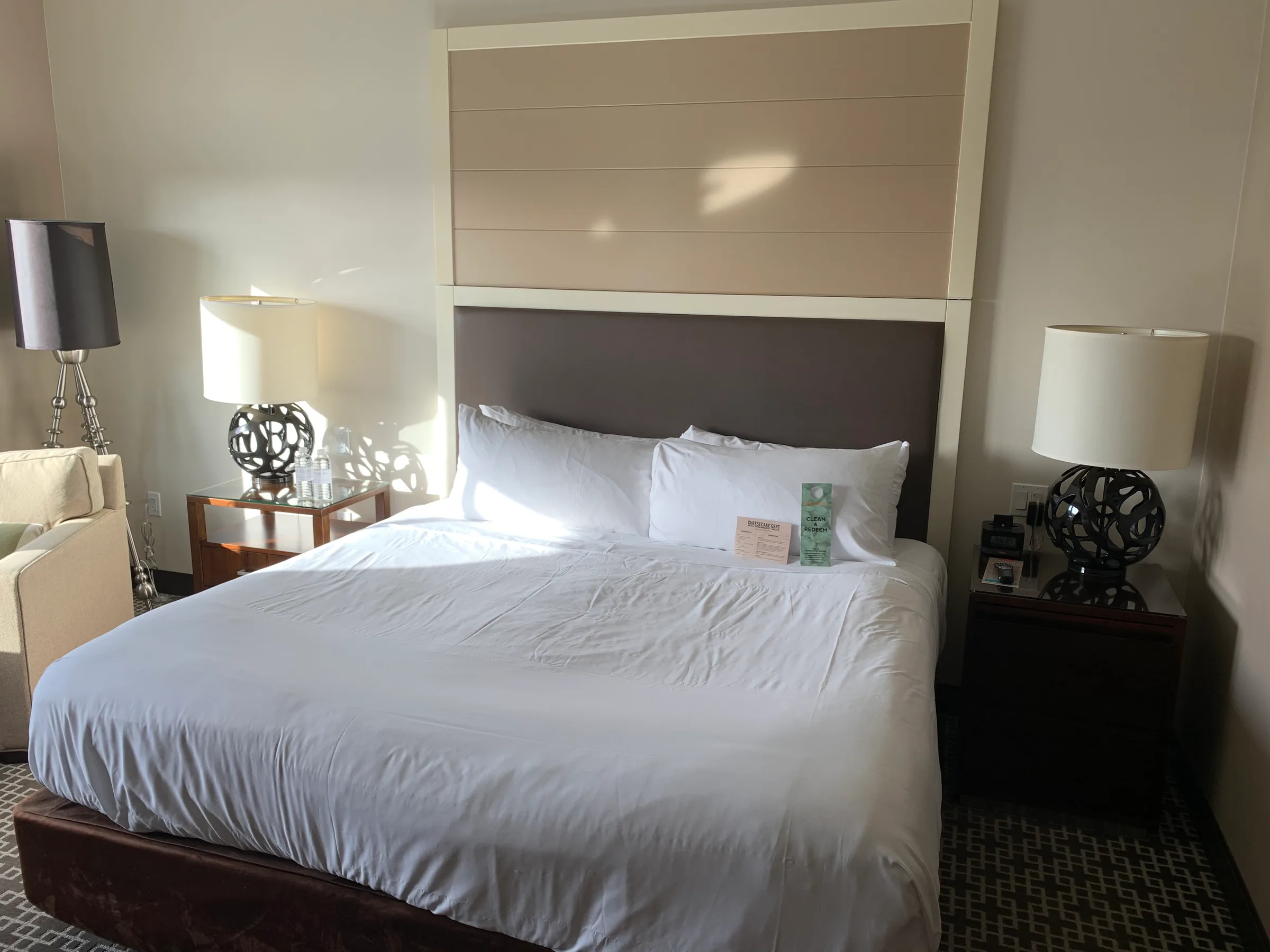Doppelbett im Hotelzimmer mit grauem Kopfteil und Nachttischen