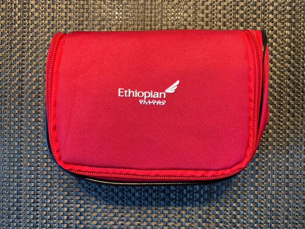 Geschlossenes rotes Ethiopian Airlines Business Class Amenity Kit auf dunklem Untergrund; weisses gesticktes Ethiopian-Logo mit stilisiertem Flügel