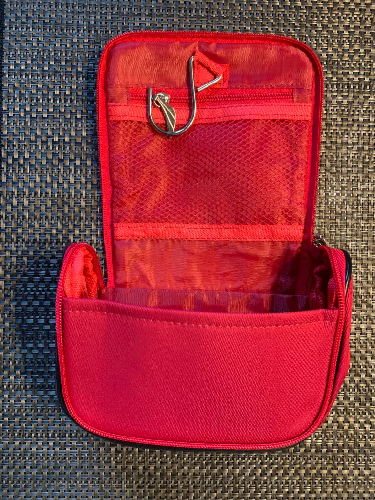 Aufgeklapptes leeres Ethiopian Airlines Amenity Kit von oben; Netzfach links, rotes Seidenfutter rechts und Reissverschluss-Innentasche in der Mitte