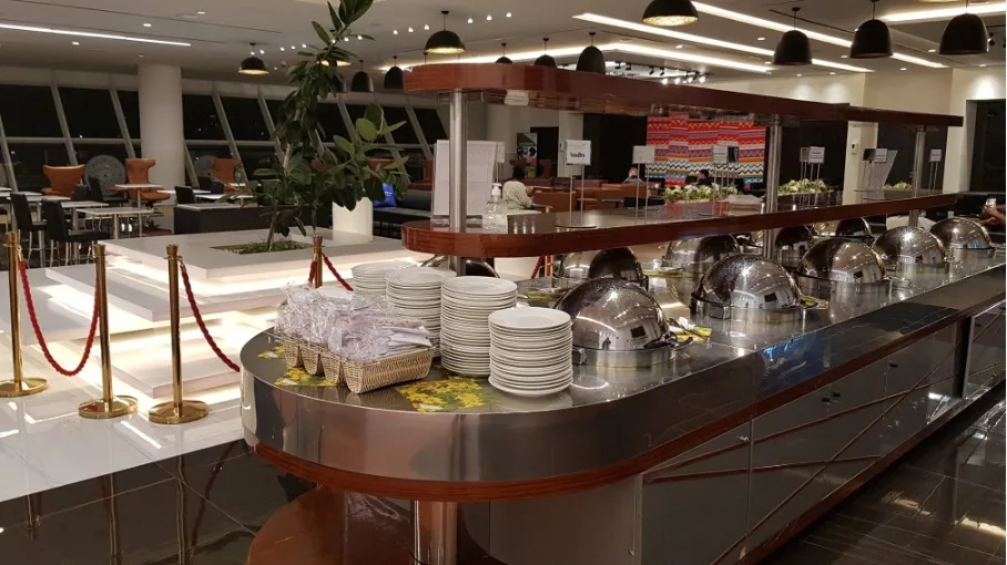 Buffet mit Tellerstapel und warmen Beleuchtungselementen im Flughafenlounge