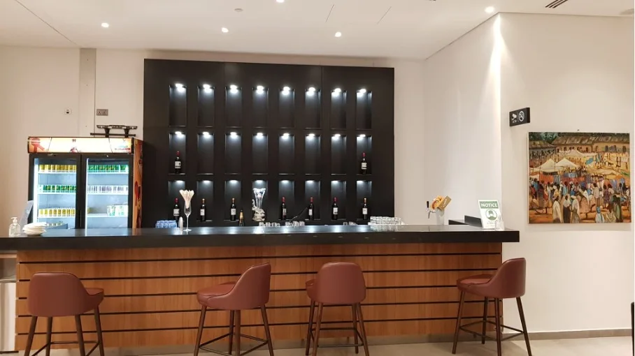 Bar mit Flaschenregalen und Stühlen im Loungebereich