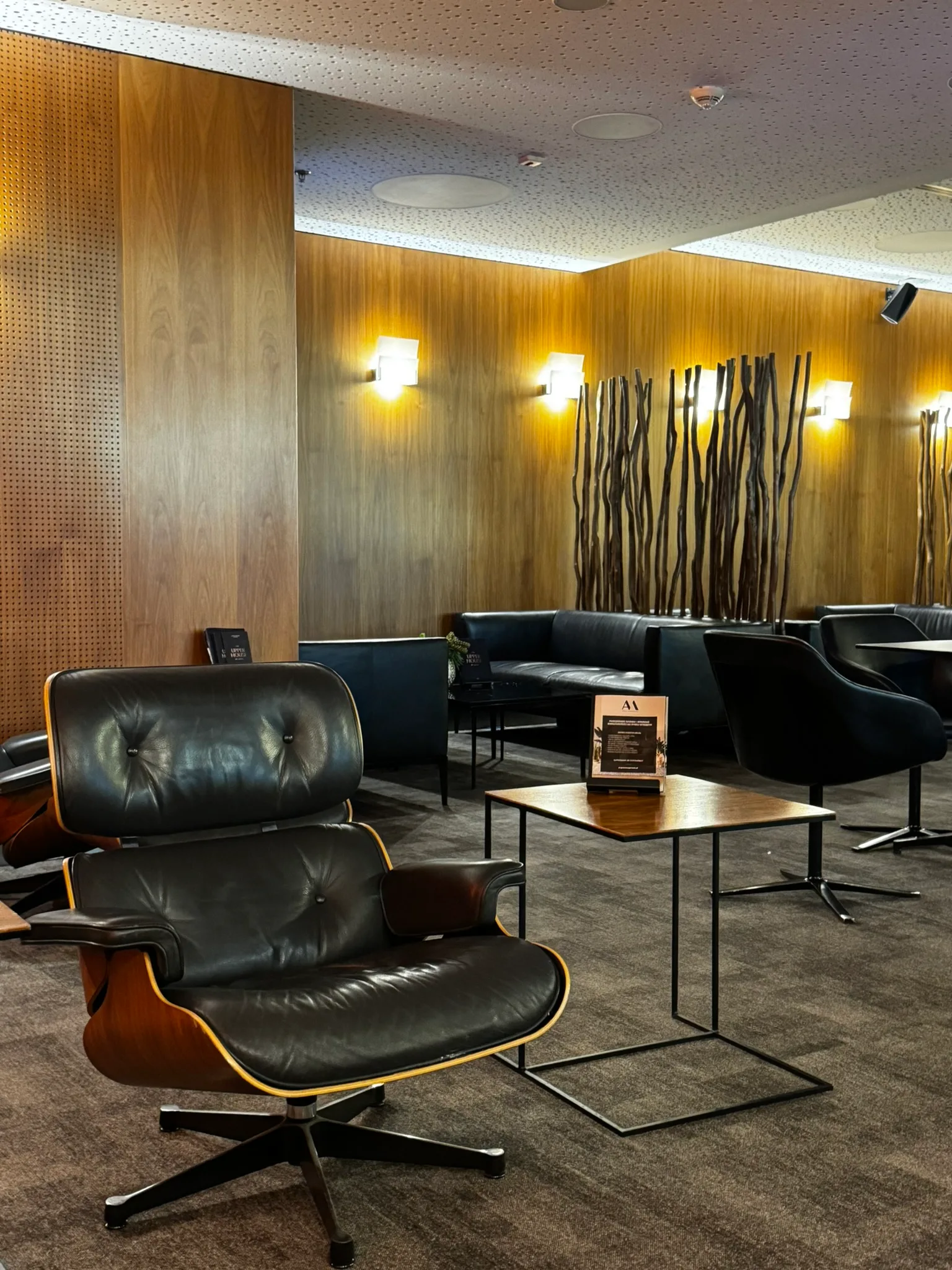 Lounge mit schwarzen Ledersesseln und Holzwänden
