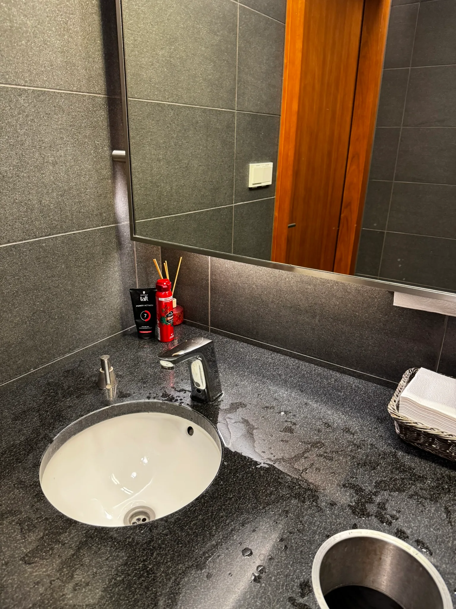 Waschbecken mit Spiegel und Kosmetikartikeln auf grauem Marmor