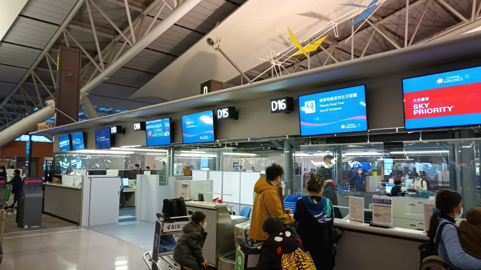 Flughafen-Schalterbereich mit Passagieren und Fluginformationsschildern