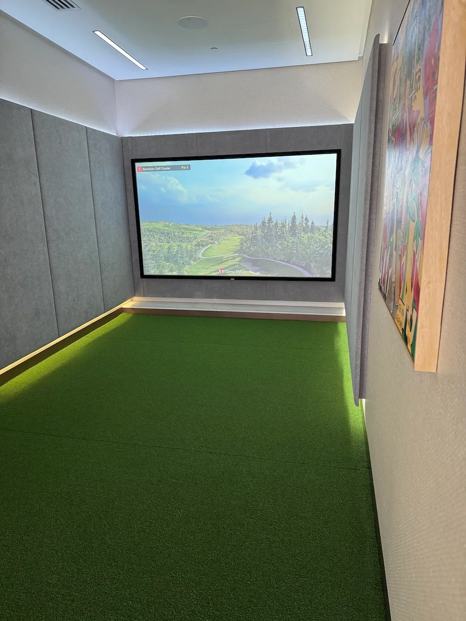 Golf-Simulatorraum mit künstlichem Grasbelag und Bildschirm