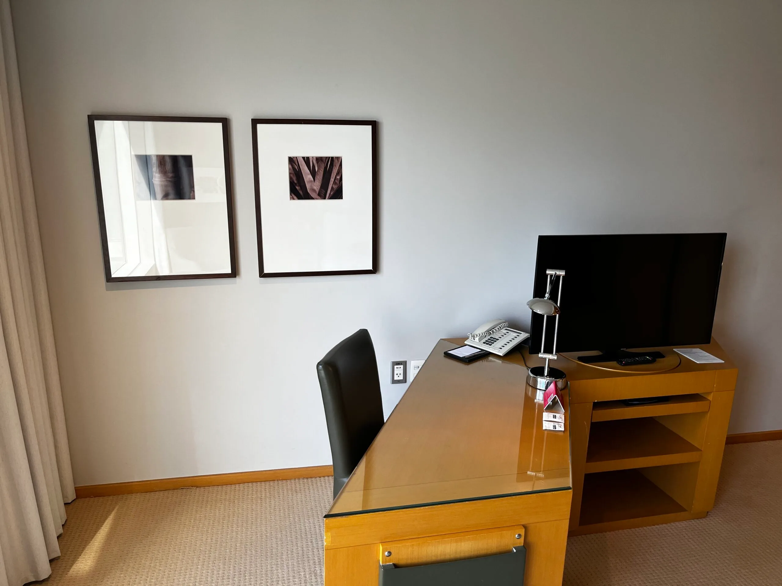 Hotelzimmer mit Schreibtisch und Fernseher an der Wand