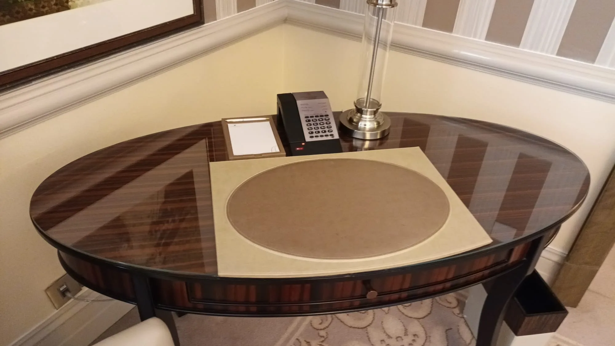 Hotelzimmer mit ovaler Glas-Tischplatte und Holzfuß